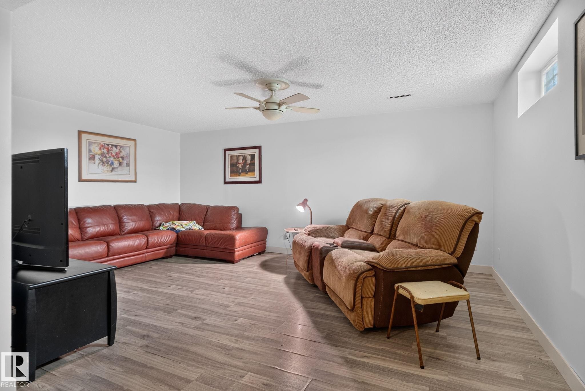 Spacious room featuring wood-finish flooring, light-toned walls, and a ceiling fan - 7539 149A Avenue Nw, Edmonton, AB - Indoor Photo Showing Living Room