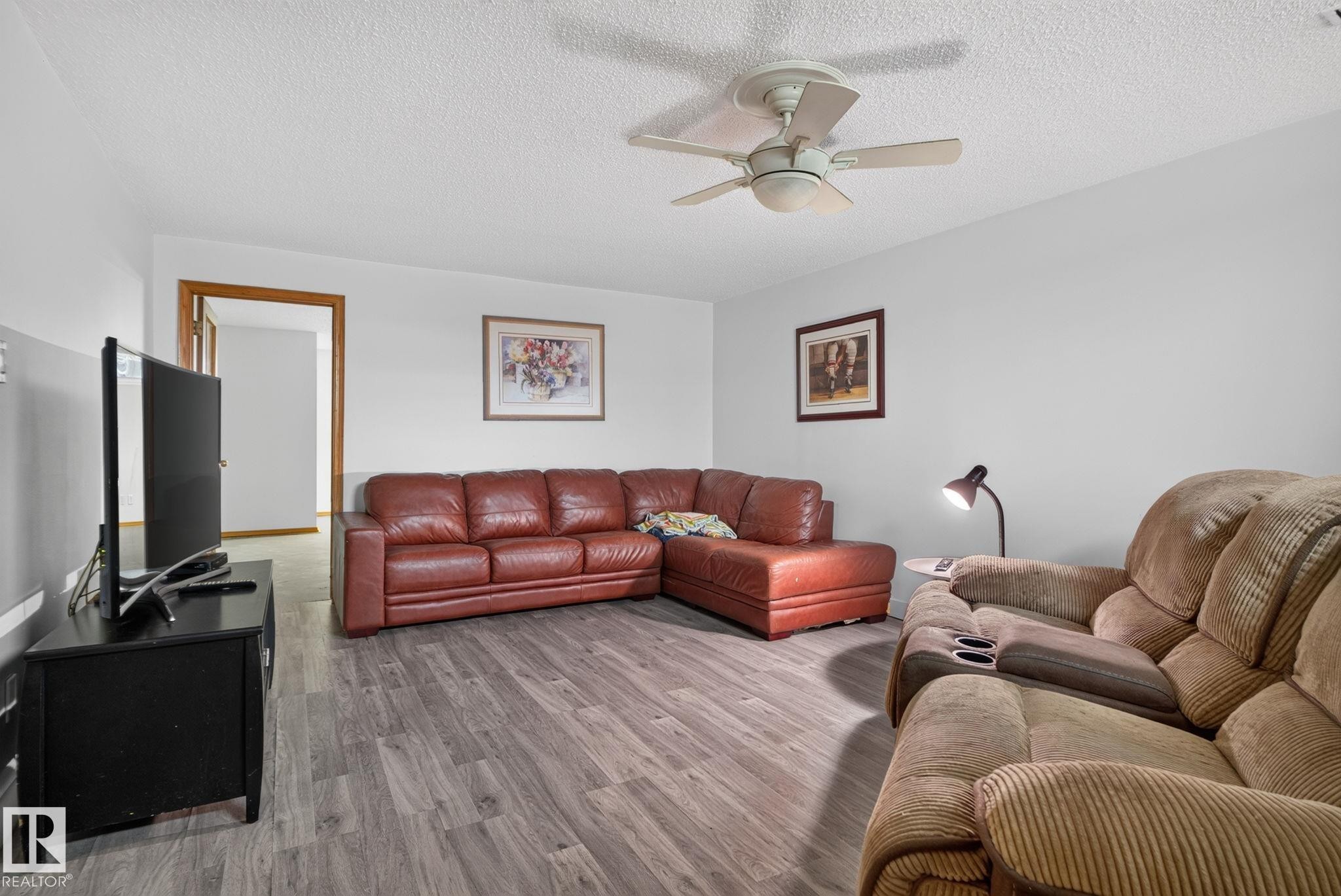 Living area featuring wood-finish flooring, light grey walls, and a ceiling fan - 7539 149A Avenue Nw, Edmonton, AB - Indoor Photo Showing Living Room