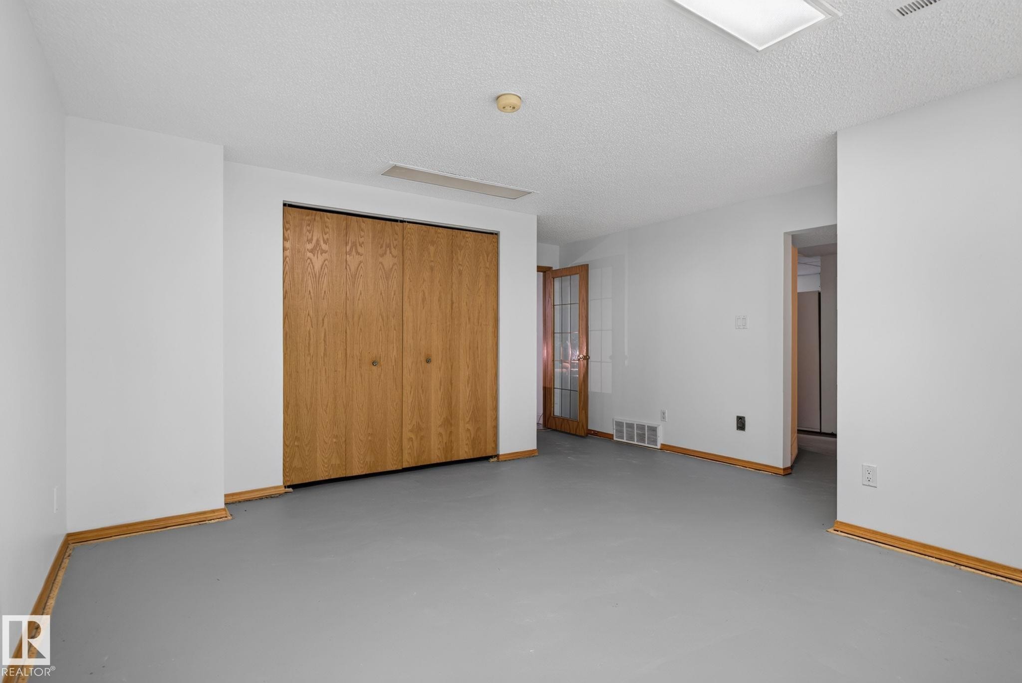 Spacious room featuring light oak bi-fold closet doors, white walls, and light wood-finish trim - 7539 149A Avenue Nw, Edmonton, AB - Indoor Photo Showing Other Room