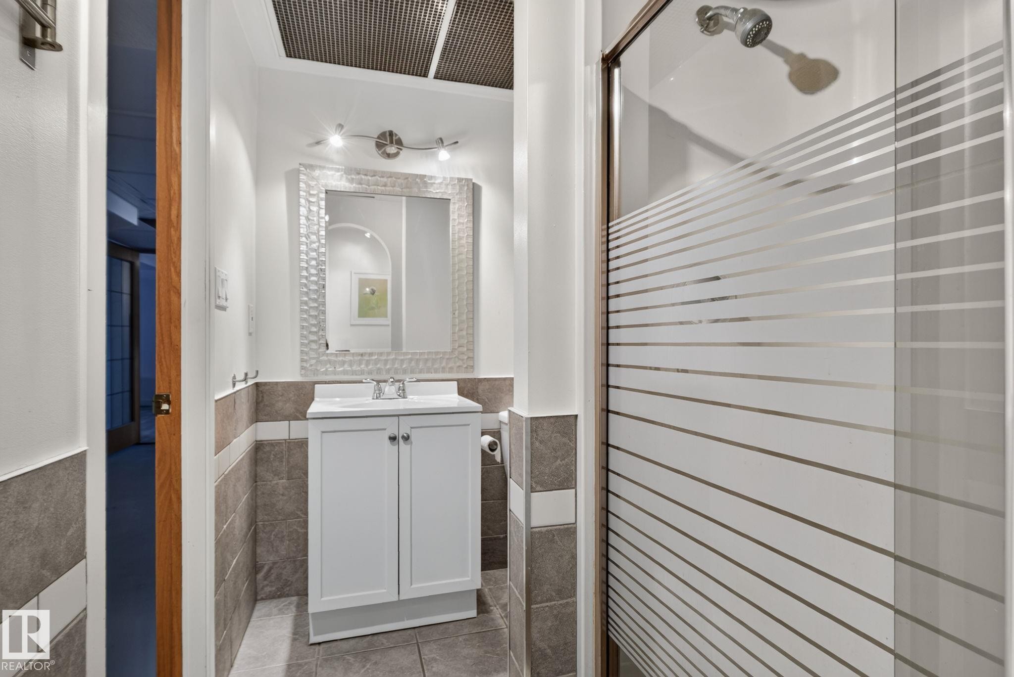 Bathroom featuring a white vanity with integrated sink, patterned mirror, and track lighting - 7539 149A Avenue Nw, Edmonton, AB - Indoor Photo Showing Bathroom