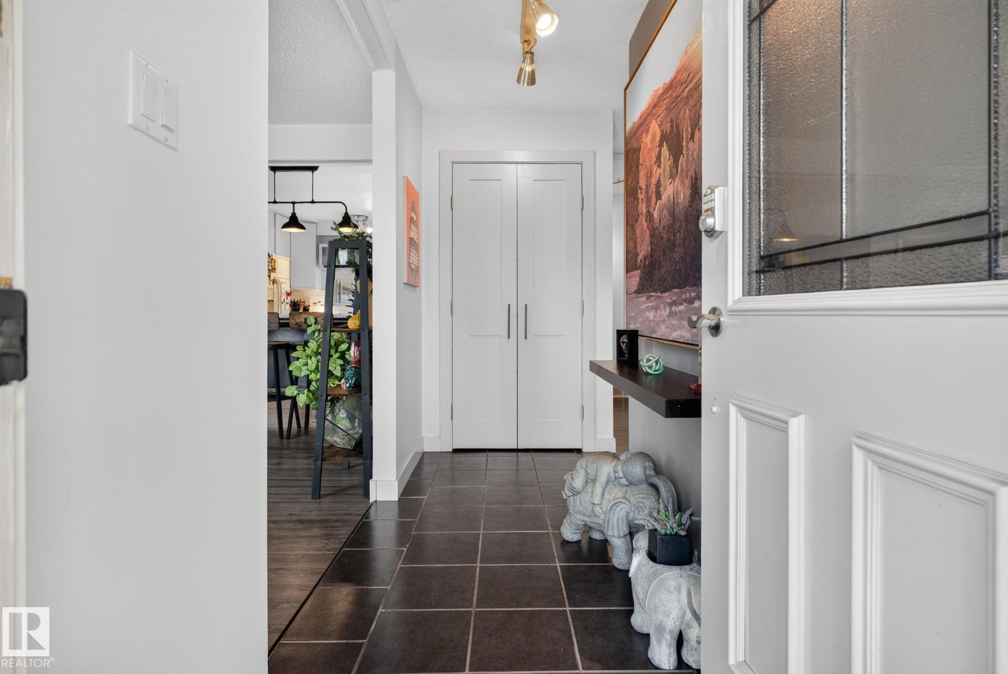 Entryway featuring dark square tile flooring, white walls, and a white paneled front door with decorative glass - 7539 149A Avenue Nw, Edmonton, AB - Indoor Photo Showing Other Room