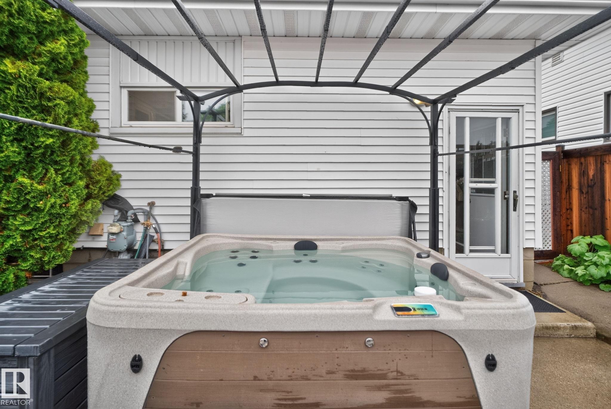 Outdoor hot tub with a protective cover, set under a metal pergola - 7539 149A Avenue Nw, Edmonton, AB - Outdoor With Exterior