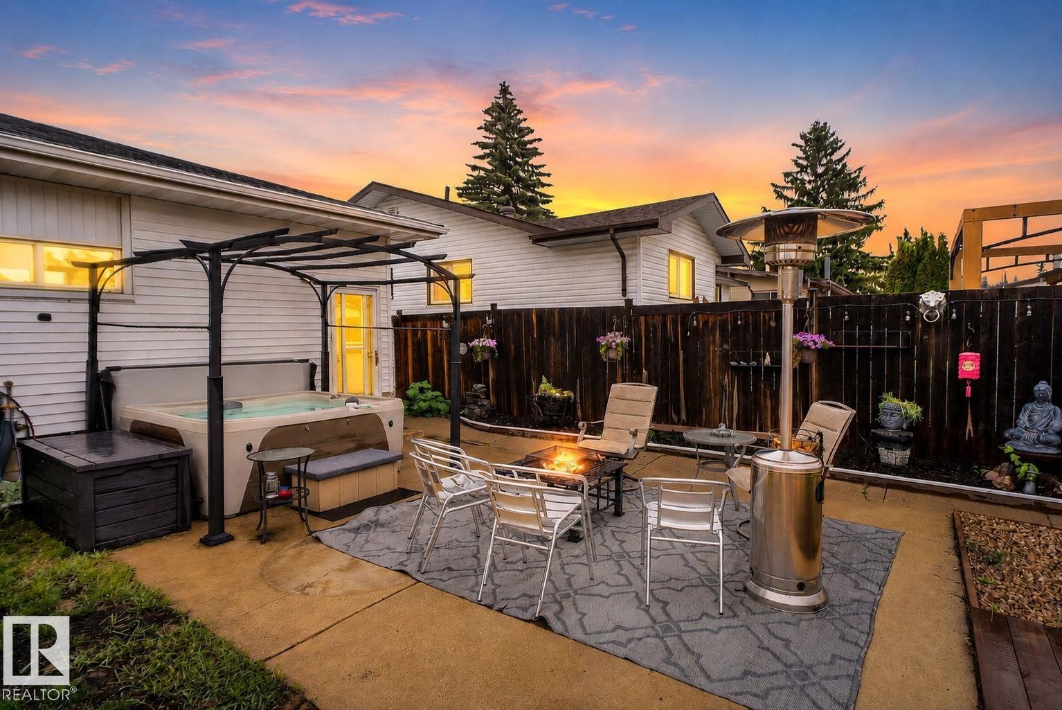 Concrete patio featuring a covered hot tub, fire pit, and privacy fencing - 7539 149A Avenue Nw, Edmonton, AB - Outdoor