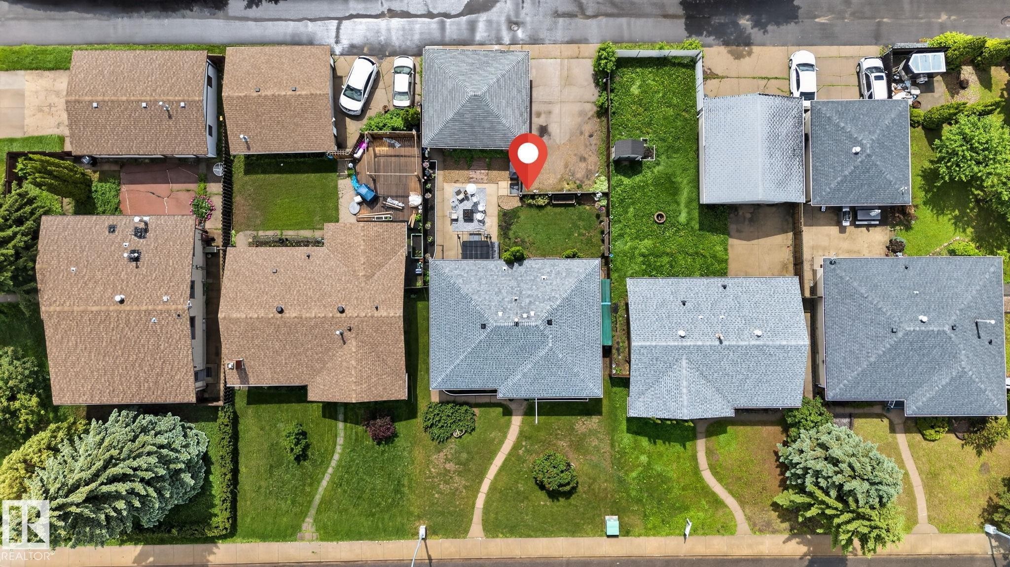 Aerial perspective showcasing a residential property with a light grey shingle roof, a paved driveway, and a backyard featuring a patio area - 7539 149A Avenue Nw, Edmonton, AB - Outdoor