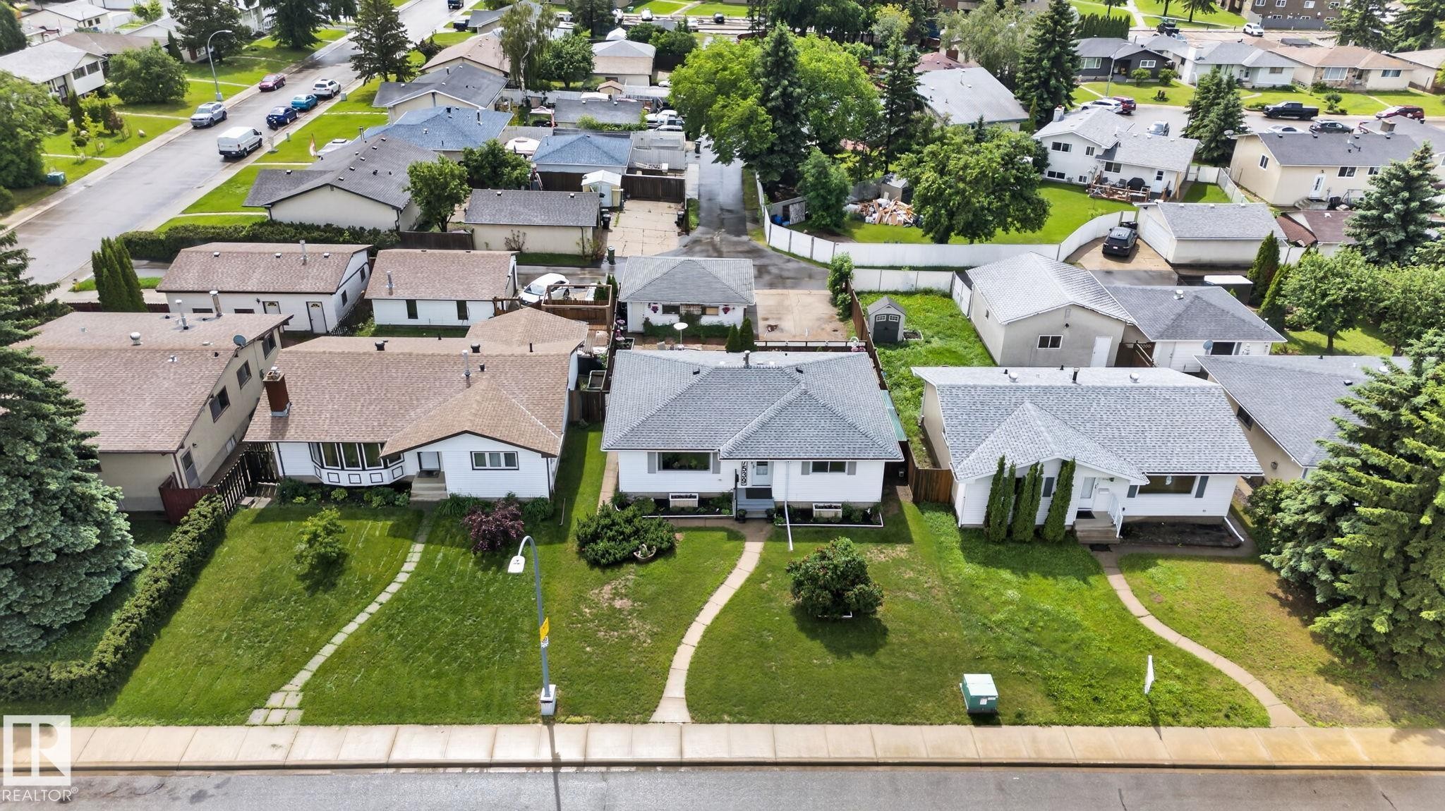 Expansive residential property featuring a manicured front lawn, mature trees, and a concrete sidewalk - 7539 149A Avenue Nw, Edmonton, AB - Outdoor With View