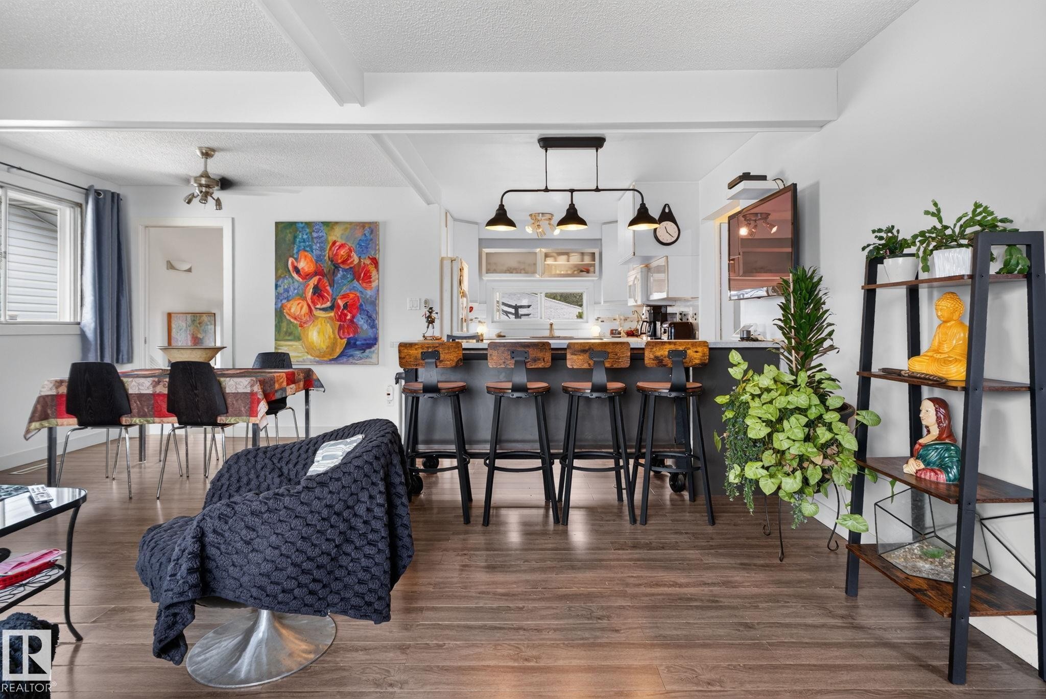 Open-concept living space featuring wood-finish flooring, a kitchen island with seating, pendant lighting, recessed lighting, and white ceiling beams - 7539 149A Avenue Nw, Edmonton, AB - Indoor
