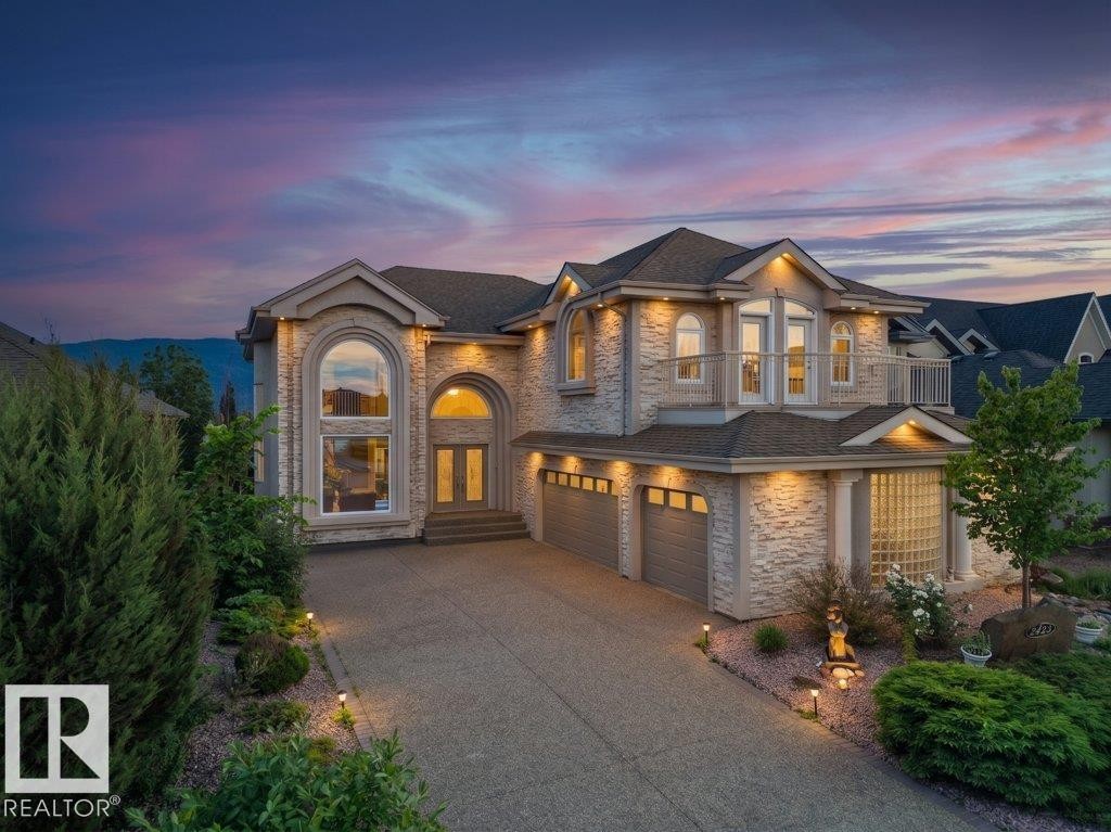 Two-story residence featuring a stone veneer exterior, an arched entryway, and a prominent arched window - 2423 Tegler Green, Edmonton, AB