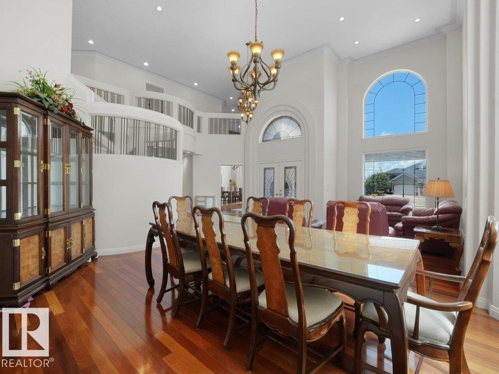Grand entry foyer featuring soaring ceilings, a sweeping staircase with custom railing, and gleaming wood-finish flooring - 2423 Tegler Green, Edmonton, AB