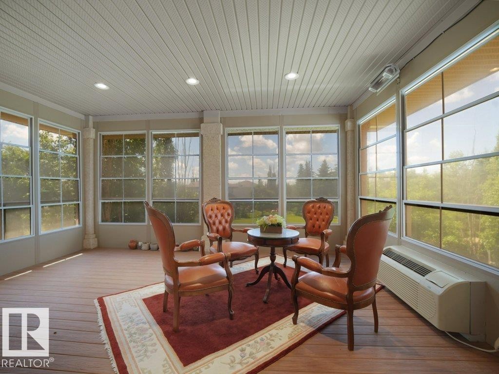 Sunroom featuring extensive window-paned walls, wood-finish flooring, and a beadboard ceiling with recessed lighting - 2423 Tegler Green, Edmonton, AB