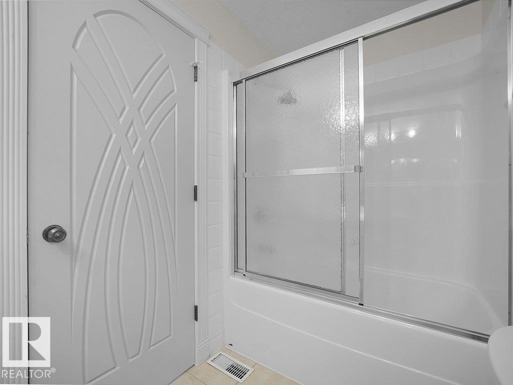 White fiberglass tub and shower enclosure with sliding frosted glass doors - 2423 Tegler Green, Edmonton, AB