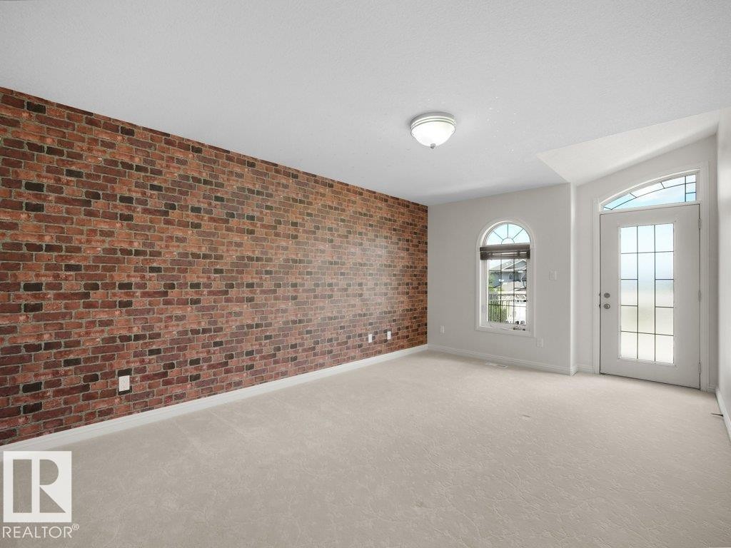 Exposed brick accent wall with a light-colored carpeted floor - 2423 Tegler Green, Edmonton, AB