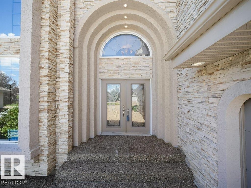 Archway entry featuring stacked stone accents and double glass-paneled doors - 2423 Tegler Green, Edmonton, AB