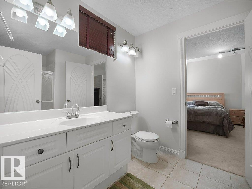 Bathroom featuring a white vanity with integrated sink, chrome faucet, and overhead lighting - 2423 Tegler Green, Edmonton, AB