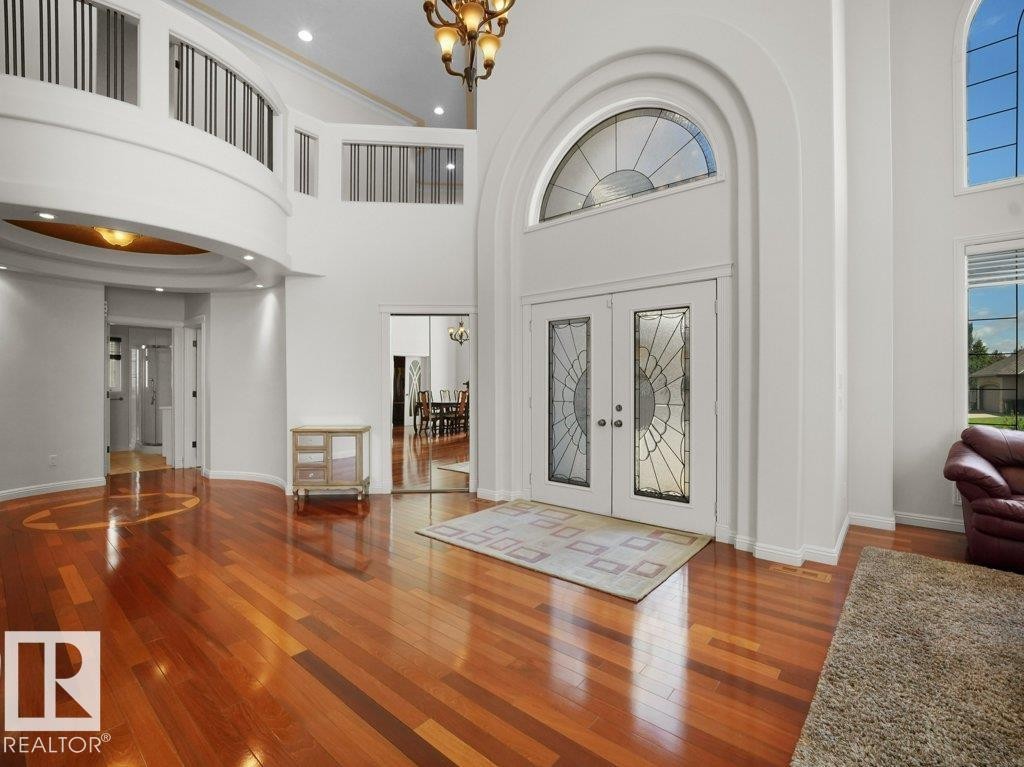 Grand entryway featuring double doors with decorative glass panels, a prominent arched transom window, and high ceilings - 2423 Tegler Green, Edmonton, AB
