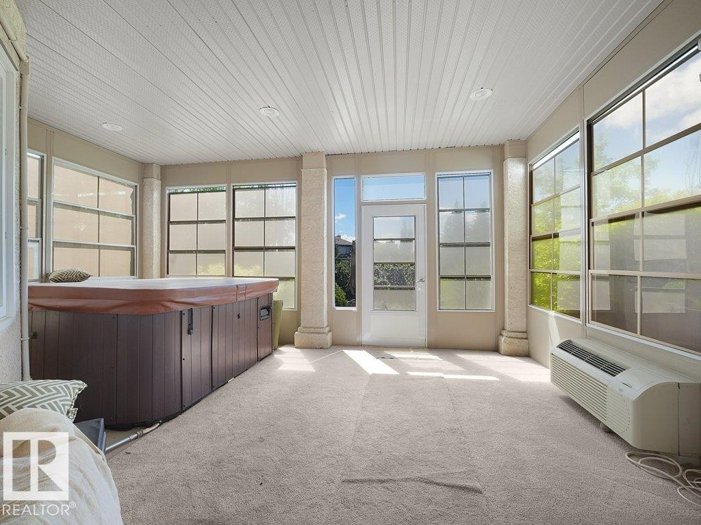 Enclosed sunroom featuring an integrated hot tub and wall-to-wall carpeting - 2423 Tegler Green, Edmonton, AB