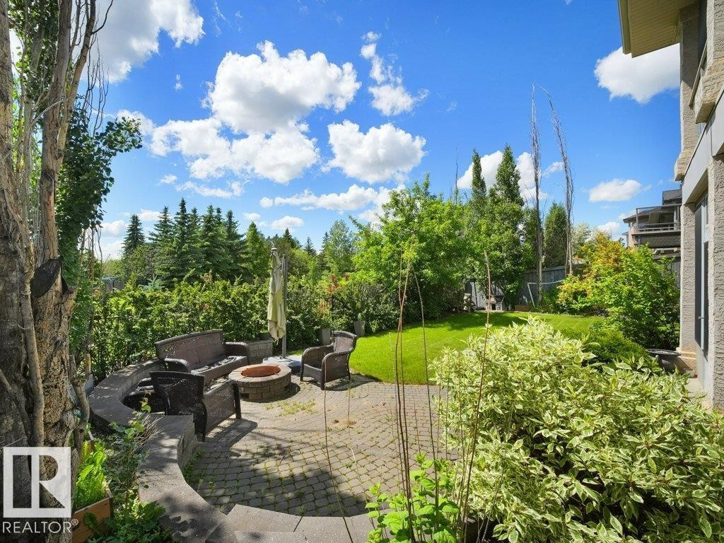 Paved patio area featuring an integrated stone fire pit and a stone retaining wall - 2423 Tegler Green, Edmonton, AB