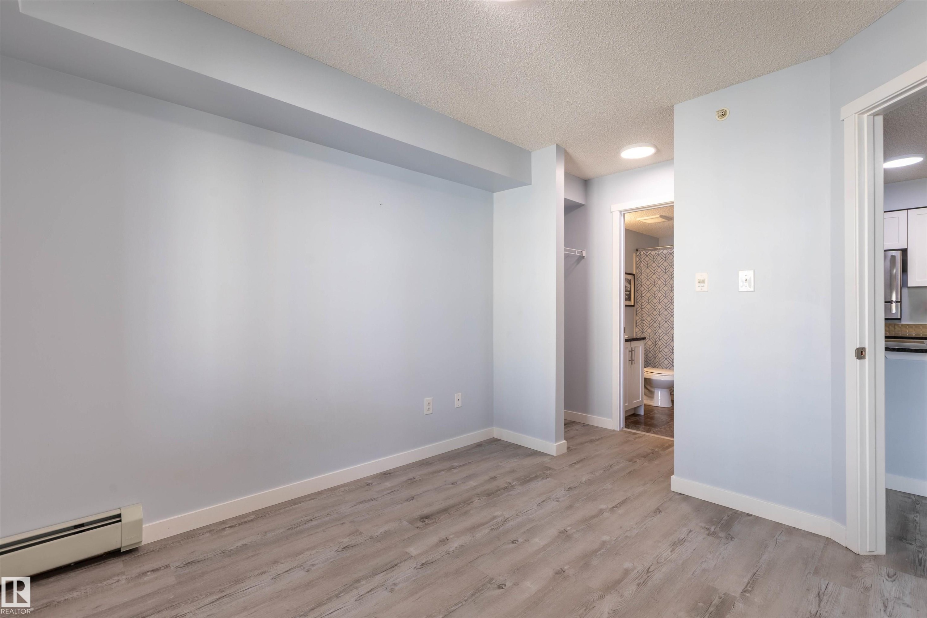 Interior space featuring wood-finish flooring, light blue wall paint, and white baseboards - 403 25 Element Dr, St. Albert, AB - Indoor Photo Showing Other Room
