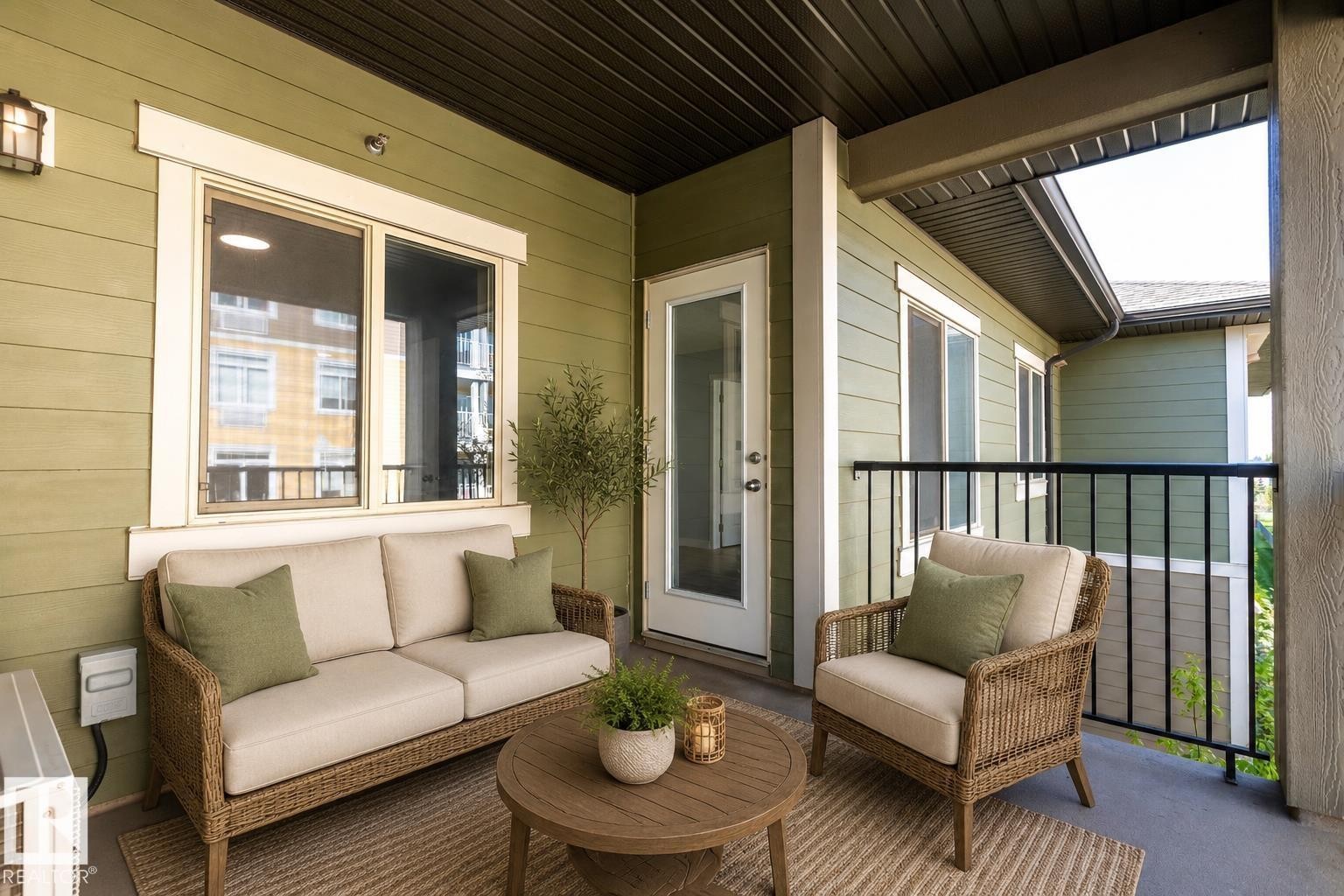 Covered balcony featuring horizontal siding, a glass-paneled door, and a black metal railing - 403 25 Element Dr, St. Albert, AB - Outdoor With Deck Patio Veranda With Exterior