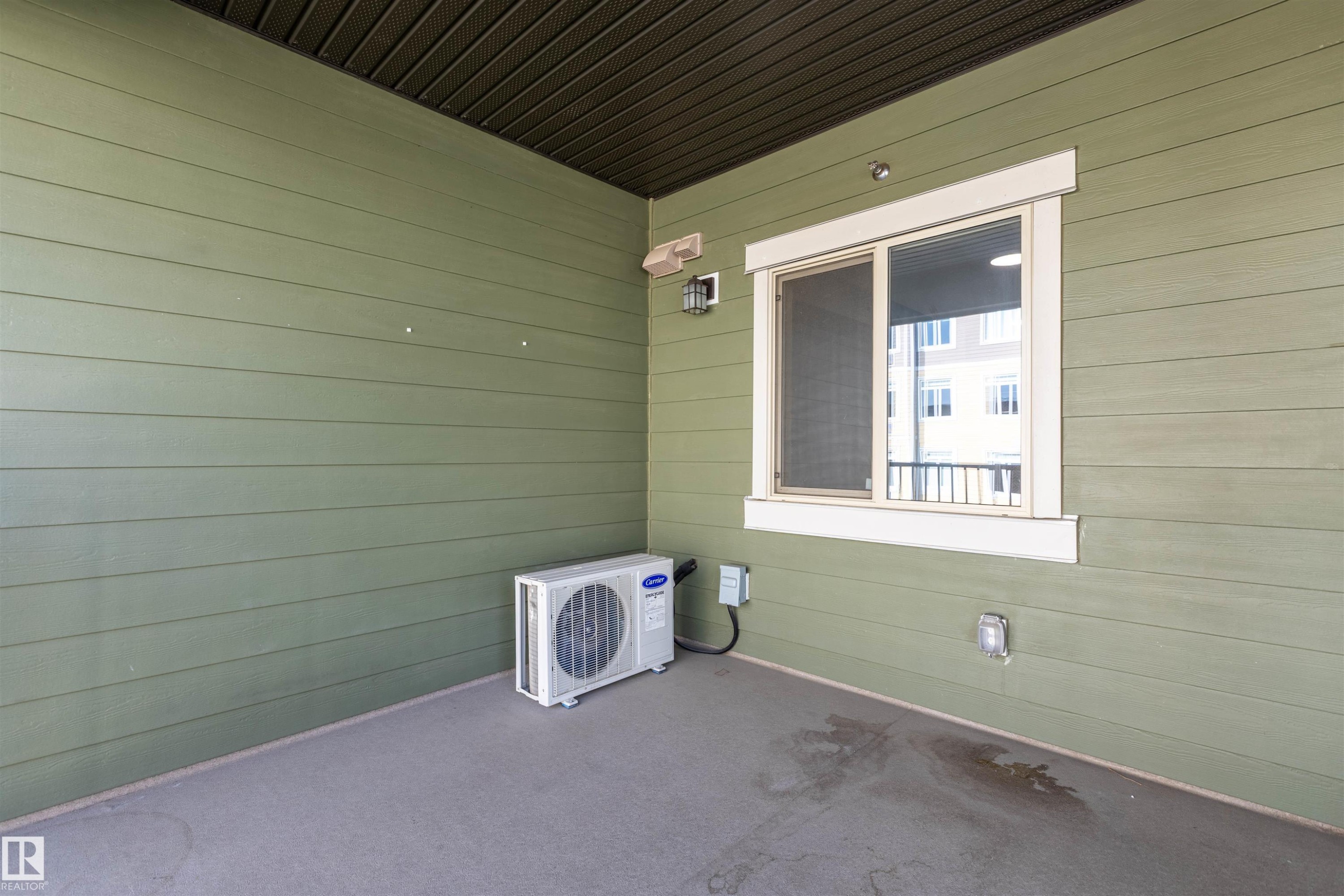Private covered patio featuring a large window, a wall-mounted exterior light fixture, and horizontal siding - 403 25 Element Dr, St. Albert, AB - Outdoor With Deck Patio Veranda With Exterior