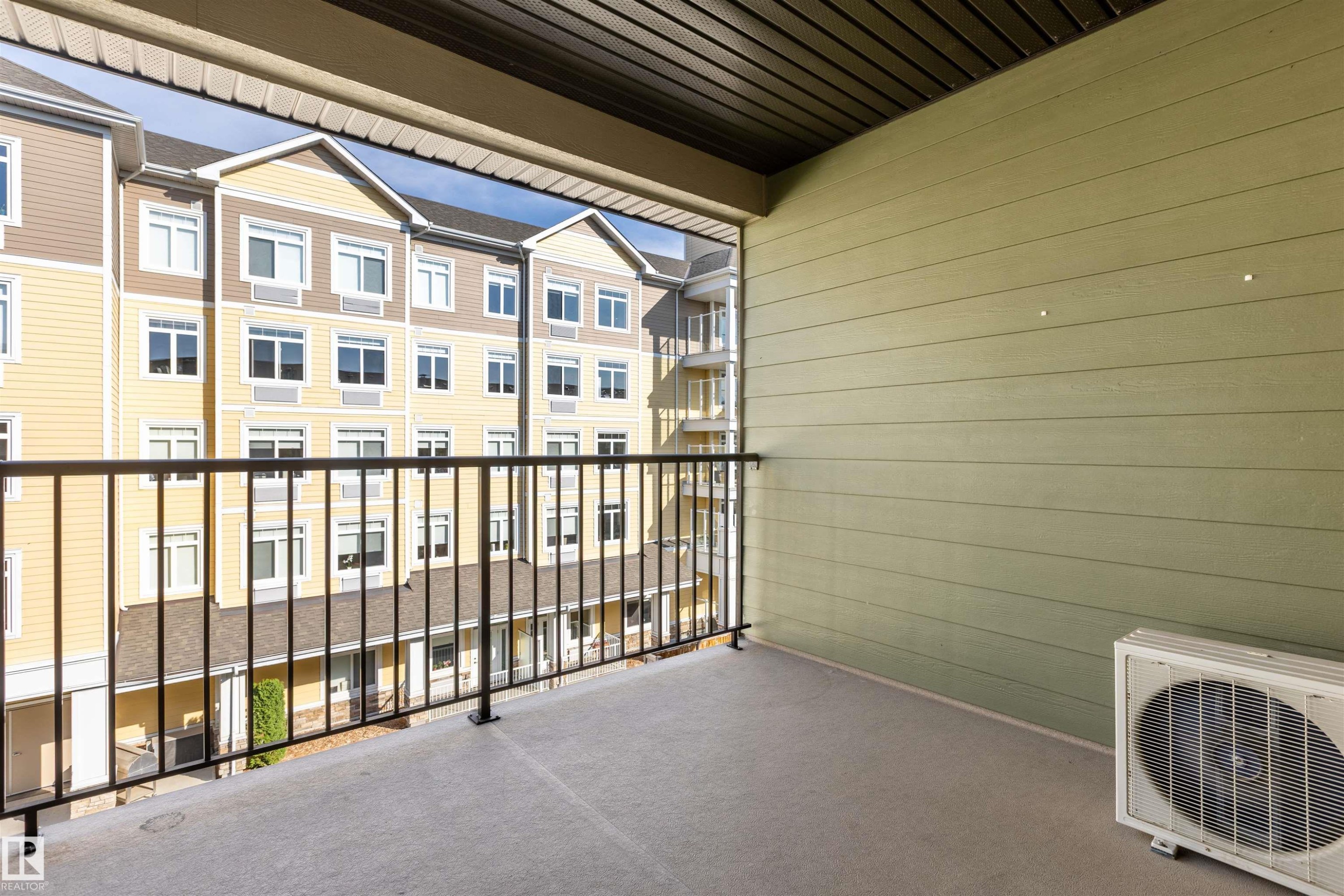 Private balcony with a concrete floor, black metal railing, and green horizontal siding - 403 25 Element Dr, St. Albert, AB - Outdoor With Exterior