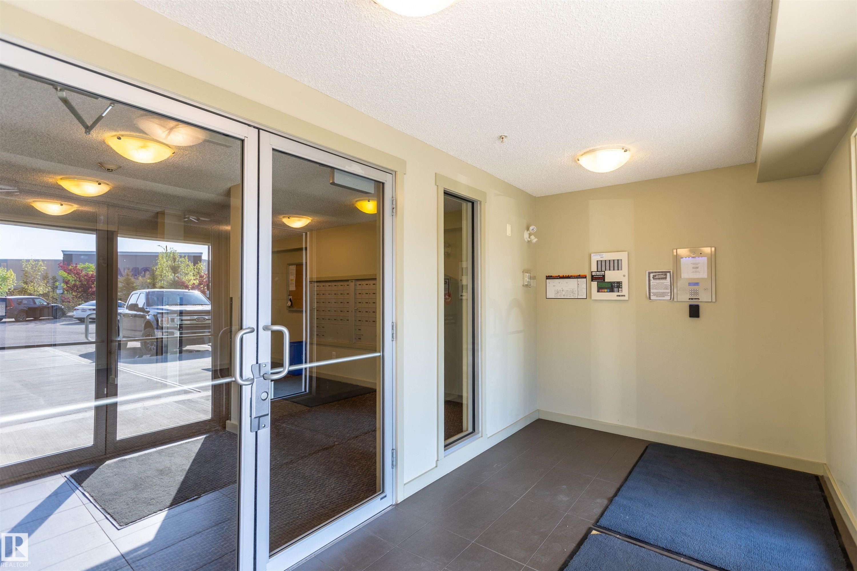 Secure entry with full-light glass doors and durable tile flooring - 403 25 Element Dr, St. Albert, AB - Indoor Photo Showing Other Room