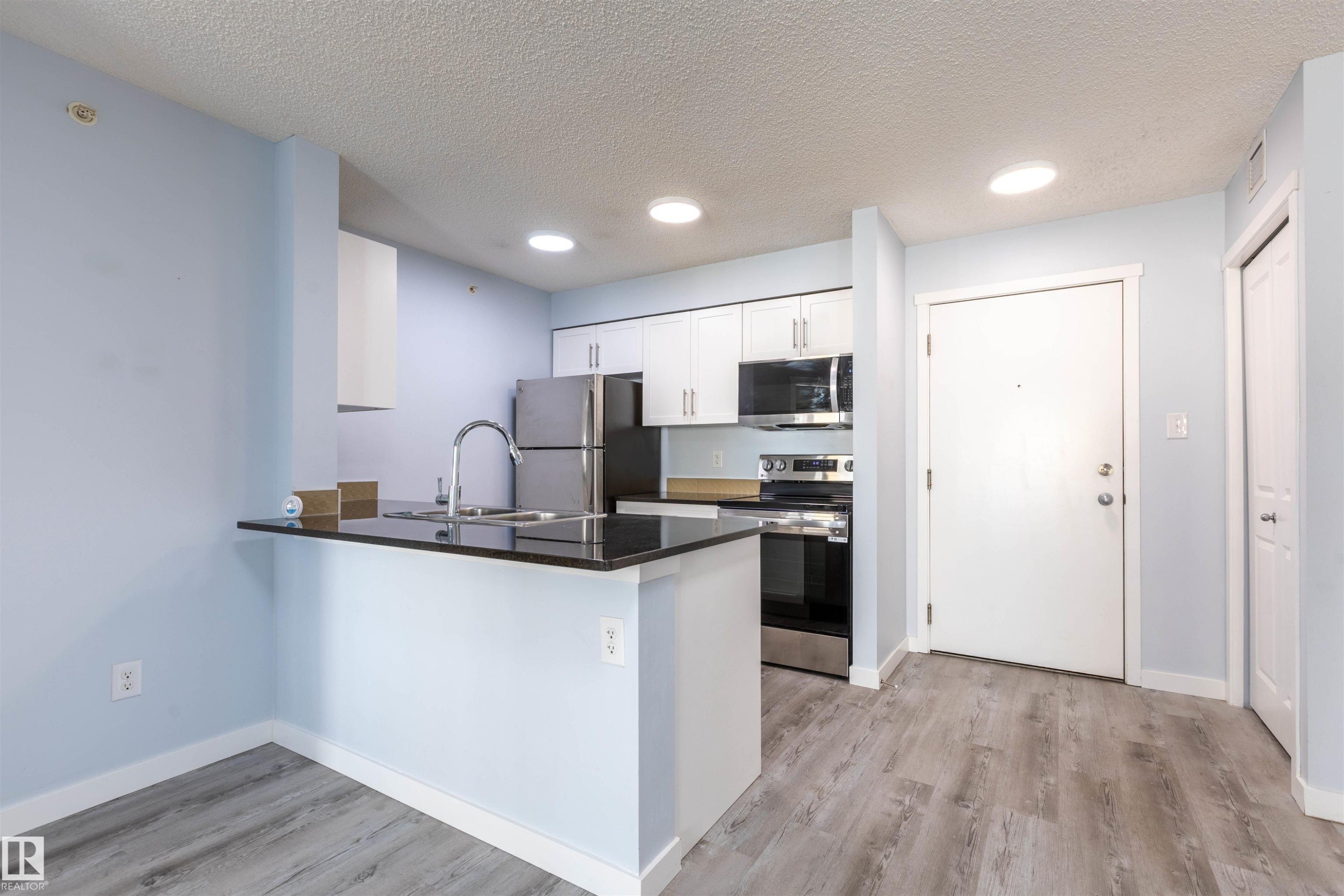 Kitchen featuring white cabinetry, stainless steel appliances, dark countertop, and an integrated breakfast bar - 403 25 Element Dr, St. Albert, AB - Indoor Photo Showing Kitchen