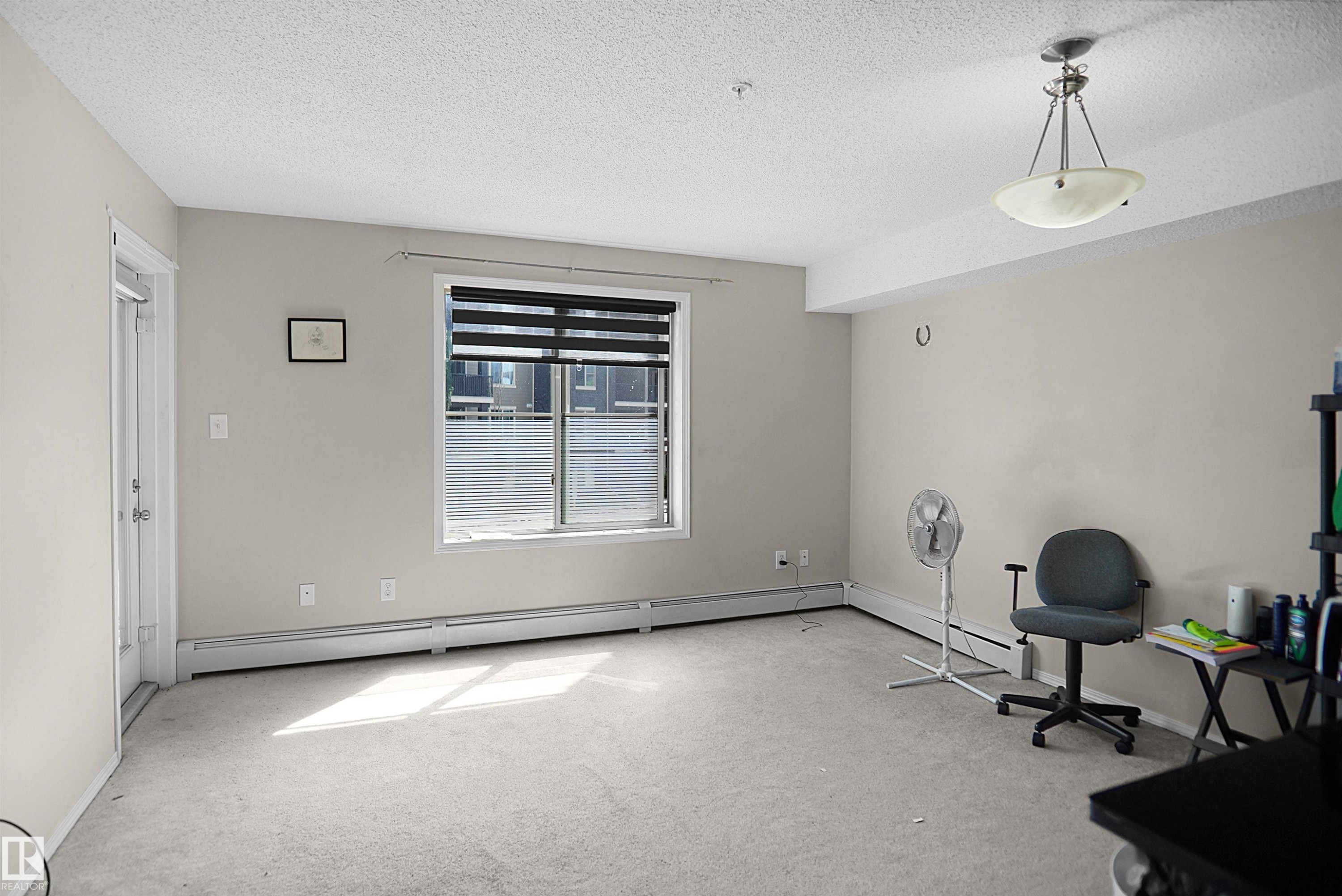 Spacious room featuring neutral painted walls and light-colored carpeting - 215 1070 Mcconachie Blvd, Edmonton, AB
