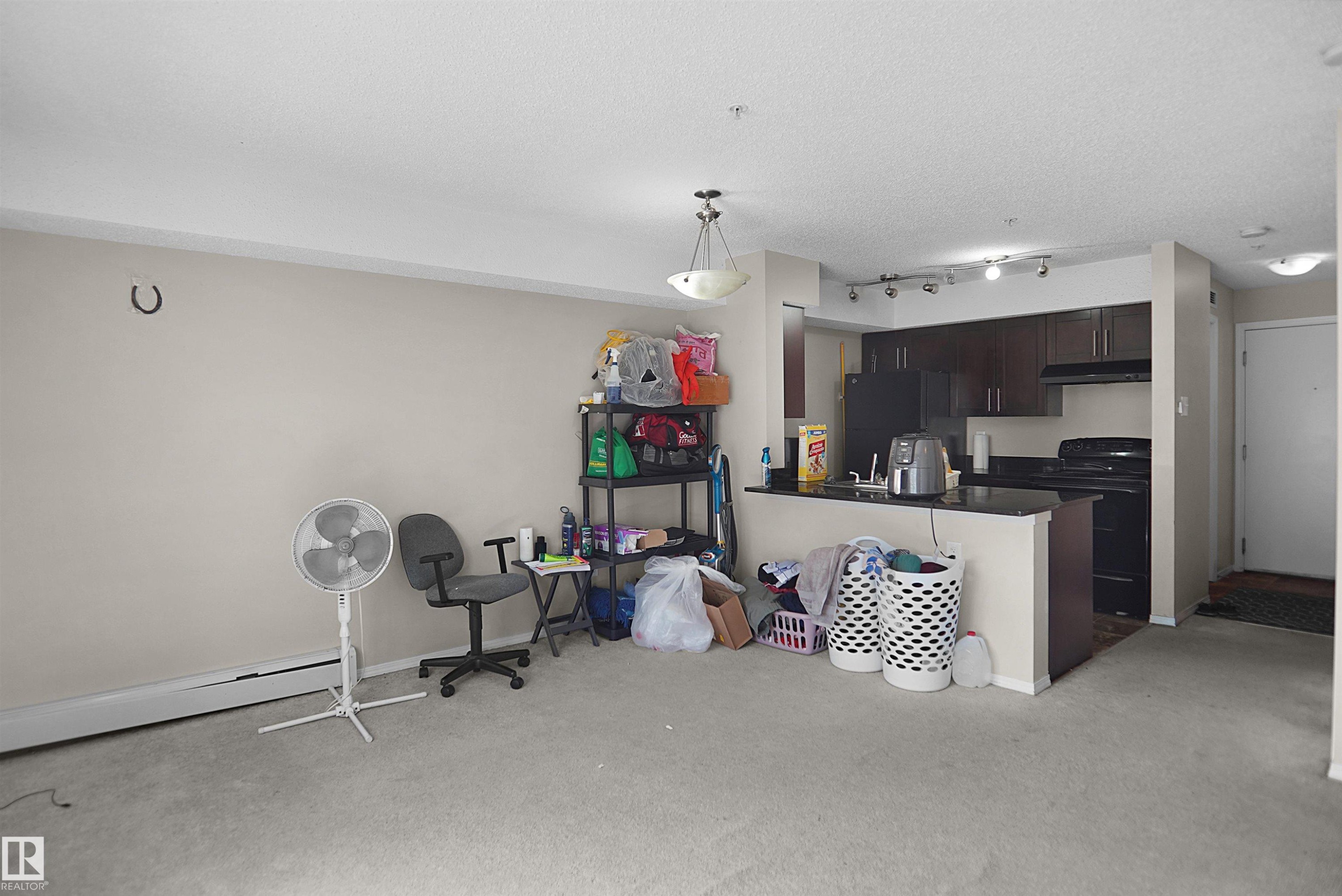 Kitchen area featuring dark wood-finish cabinetry, black appliances, and a black countertop - 215 1070 Mcconachie Blvd, Edmonton, AB