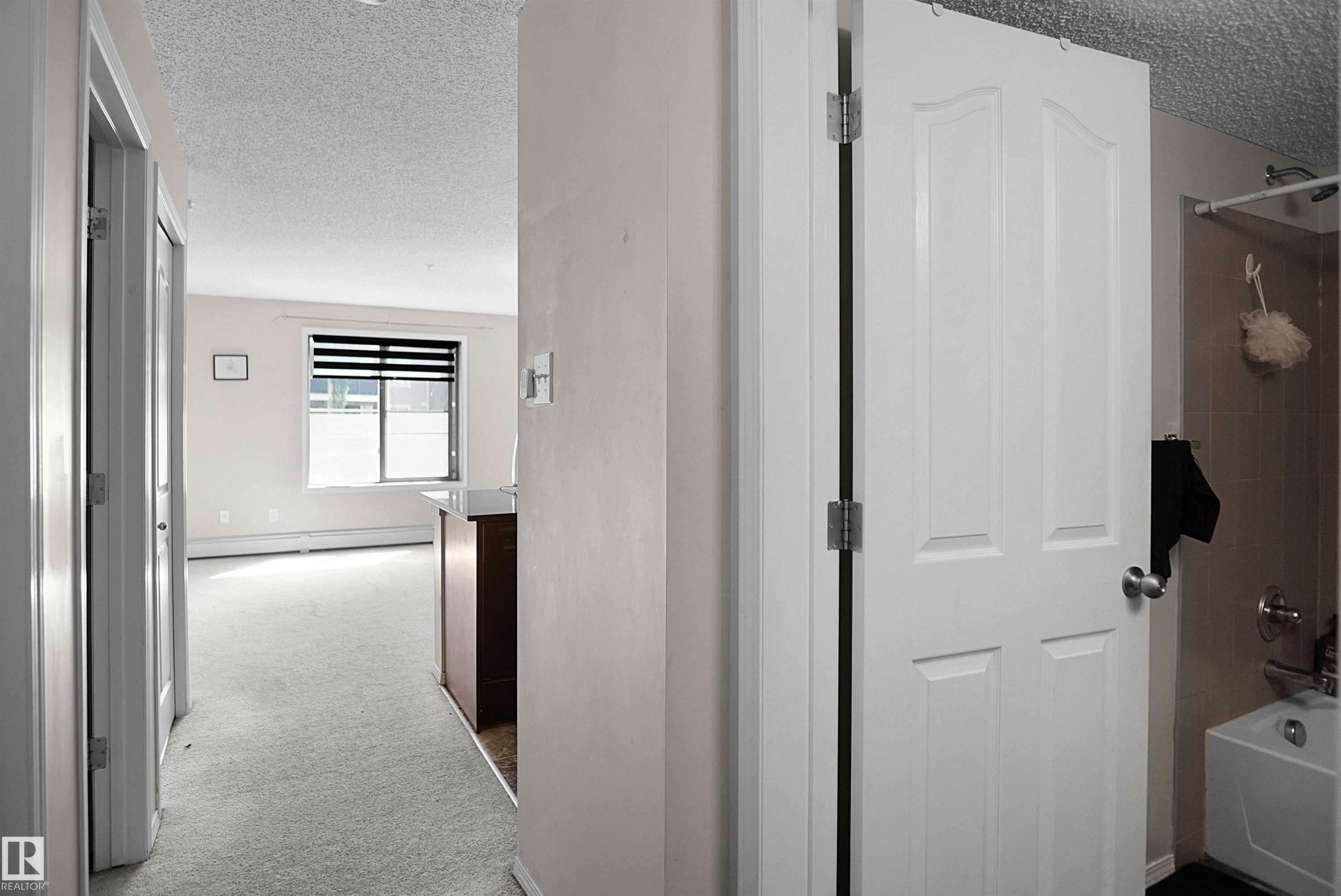 Interior hallway with light-colored walls and carpeted flooring - 215 1070 Mcconachie Blvd, Edmonton, AB