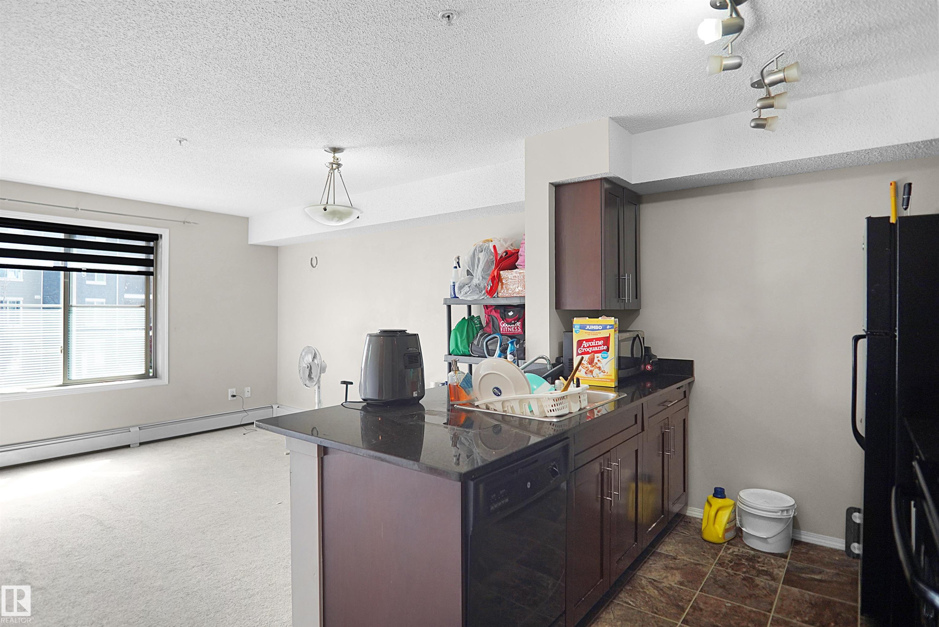 Kitchen featuring dark cabinetry, dark countertops, and a built-in dishwasher - 215 1070 Mcconachie Blvd, Edmonton, AB