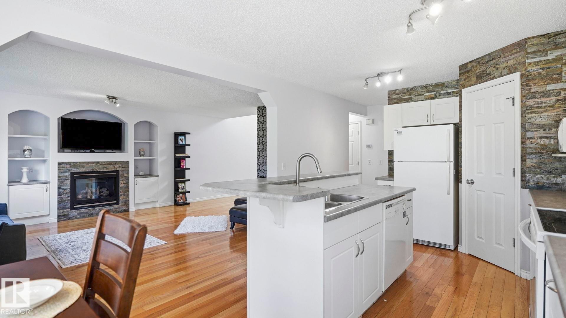 Kitchen island with integrated sink, white cabinetry, and light-toned countertops - 3591 Mclean Crescent, Edmonton, AB