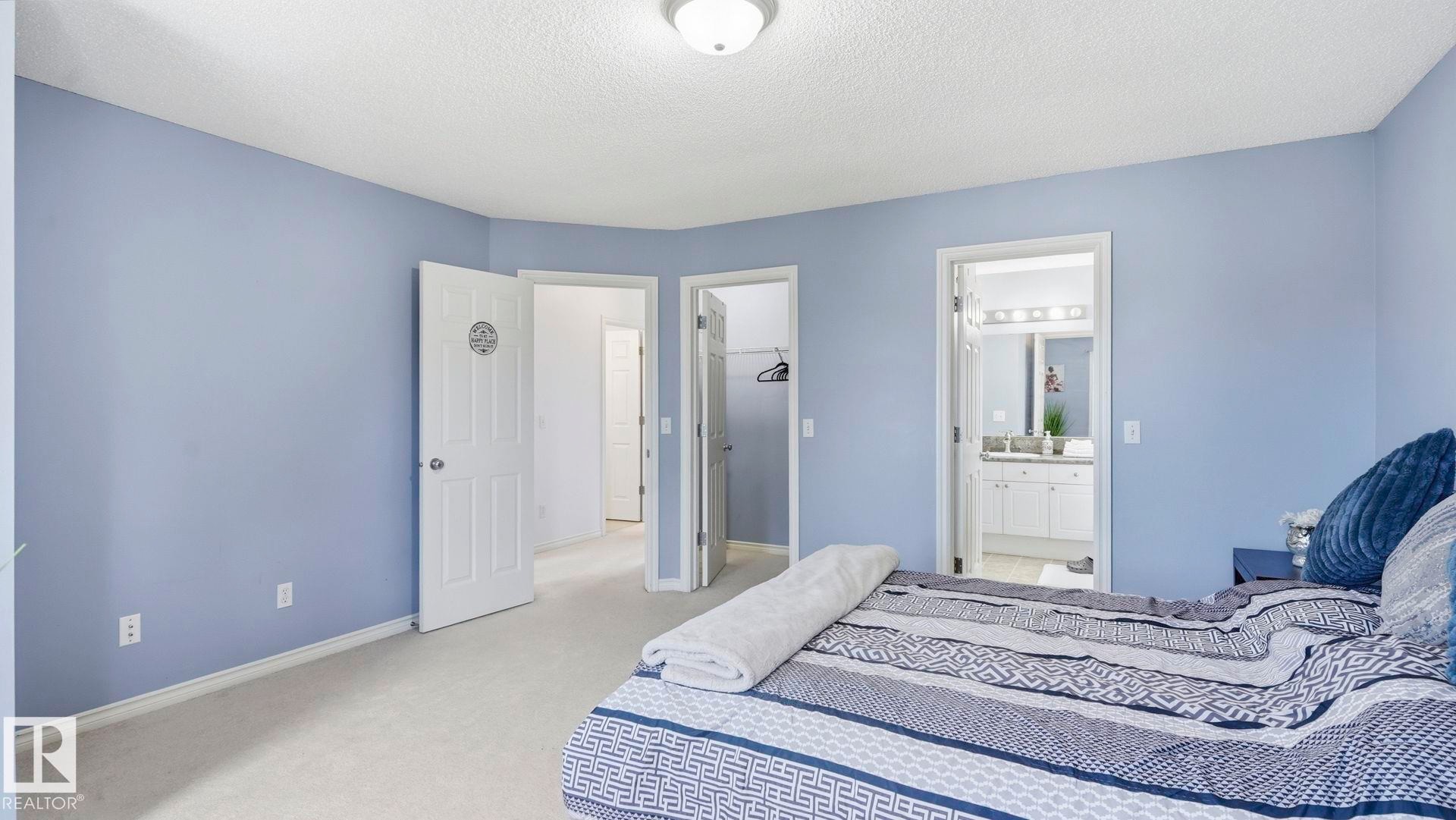 Carpeted bedroom featuring periwinkle walls, a ceiling-mounted light fixture, and white trim - 3591 Mclean Crescent, Edmonton, AB