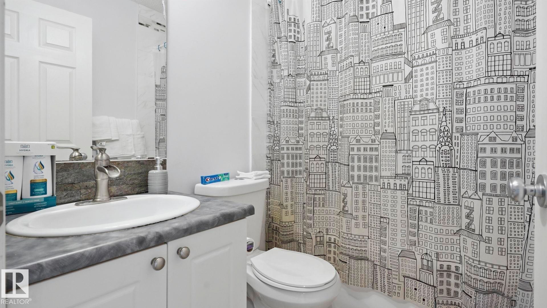 Bathroom featuring a white vanity with a dark countertop, an undermount sink, and a brushed nickel faucet - 3591 Mclean Crescent, Edmonton, AB