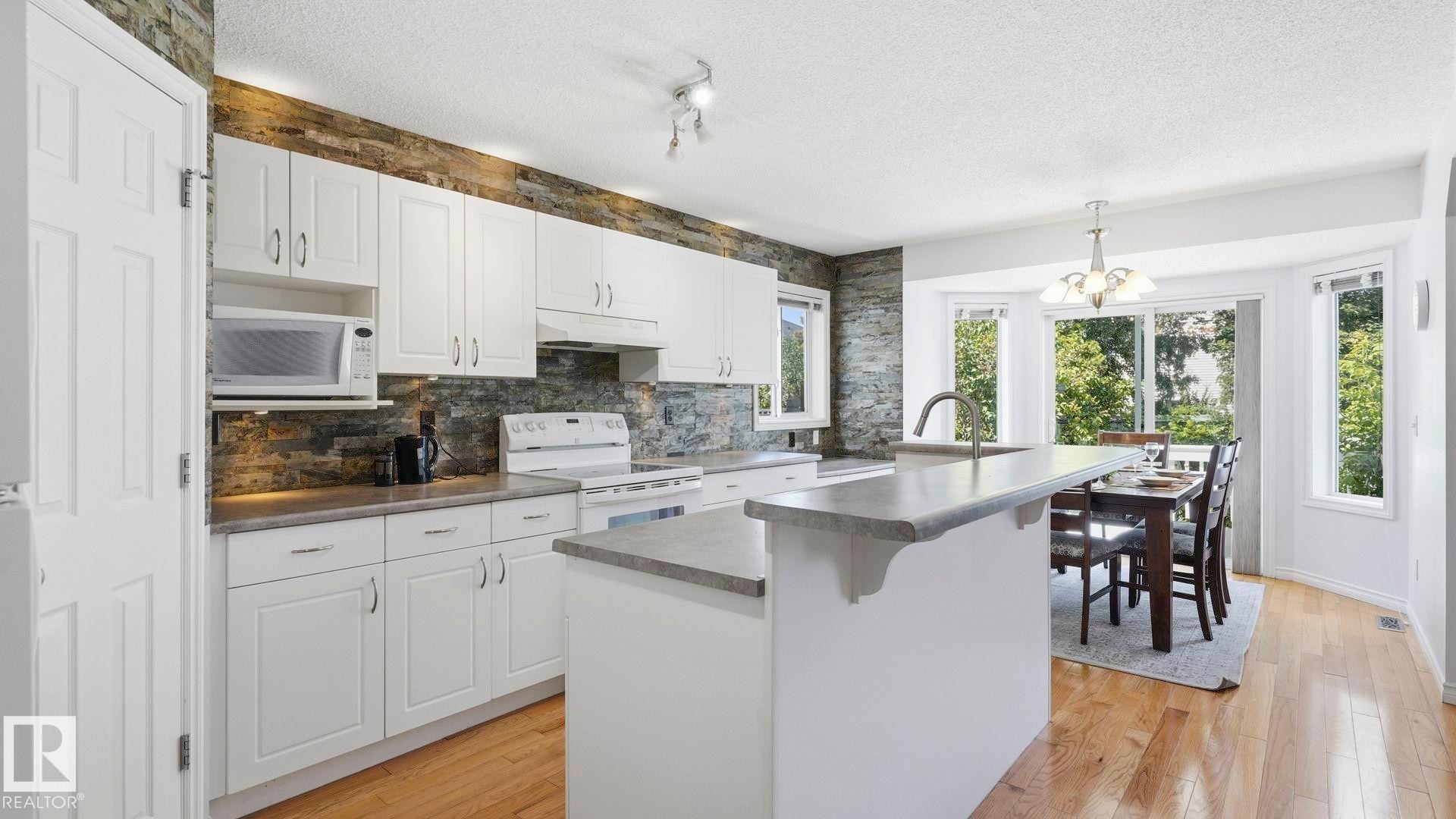 Modern kitchen with white cabinetry and stone backsplash - 3591 Mclean Crescent, Edmonton, AB