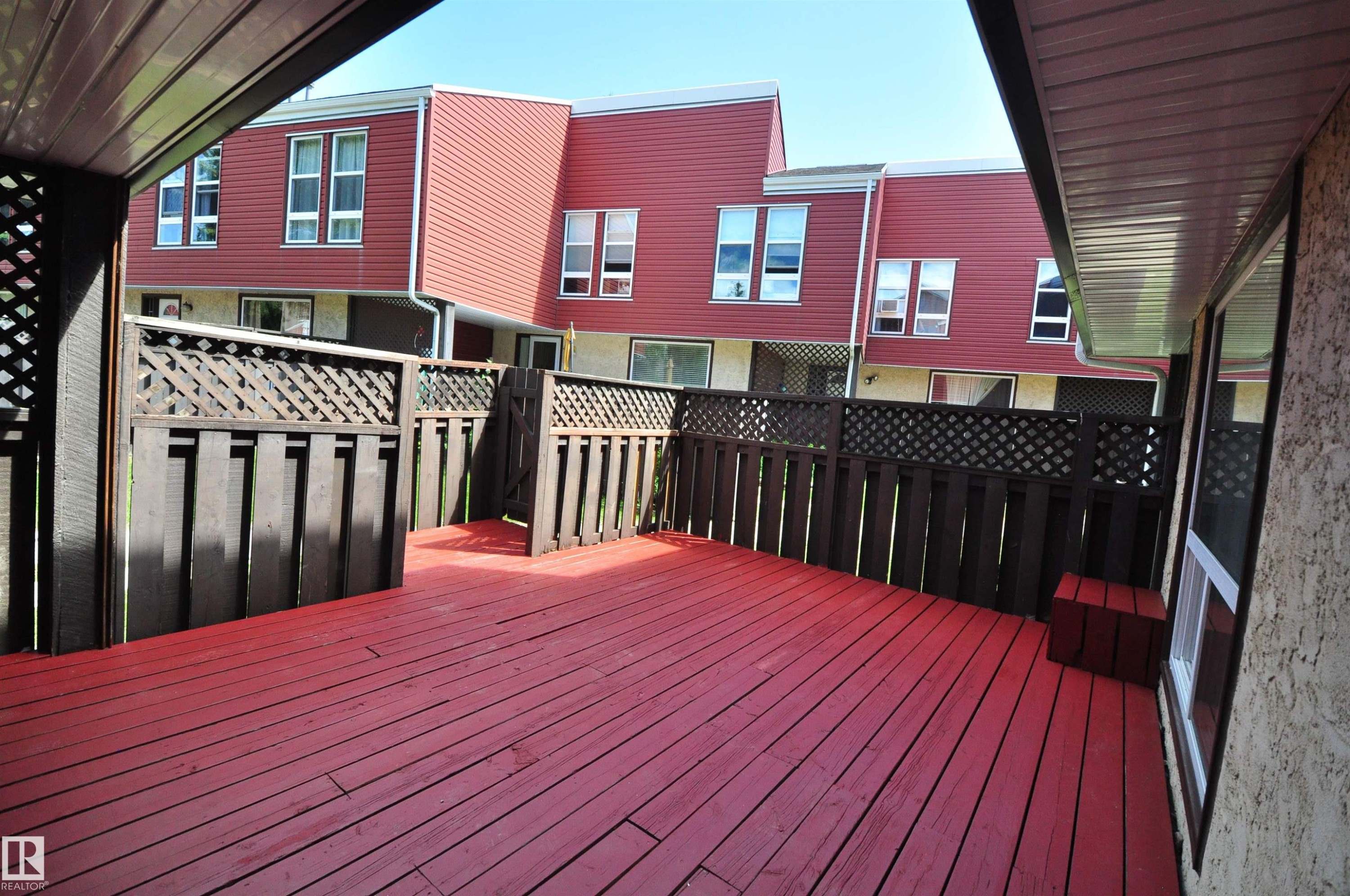 Spacious outdoor deck with rich red wood-finish flooring and dark wood privacy fencing - 617 Millbourne Road E, Edmonton, AB