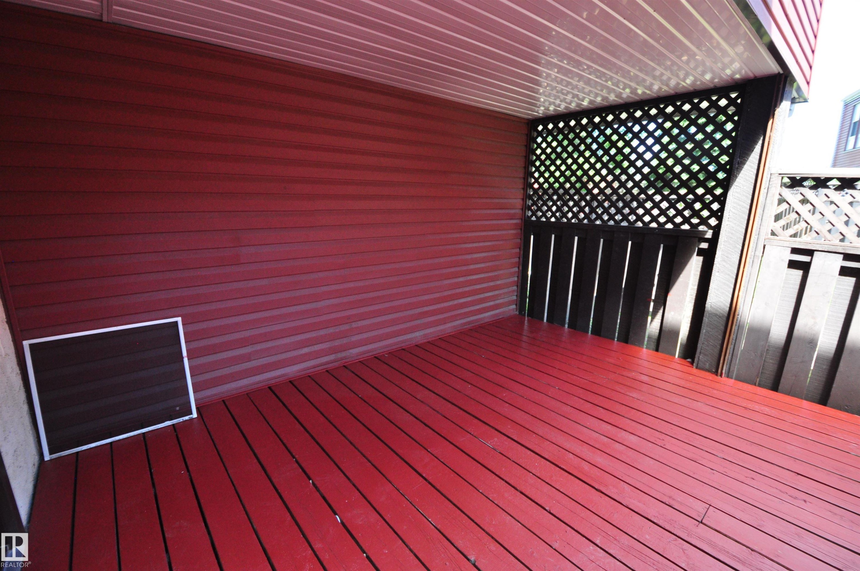 Covered outdoor space featuring red wood-finish decking and red siding - 617 Millbourne Road E, Edmonton, AB