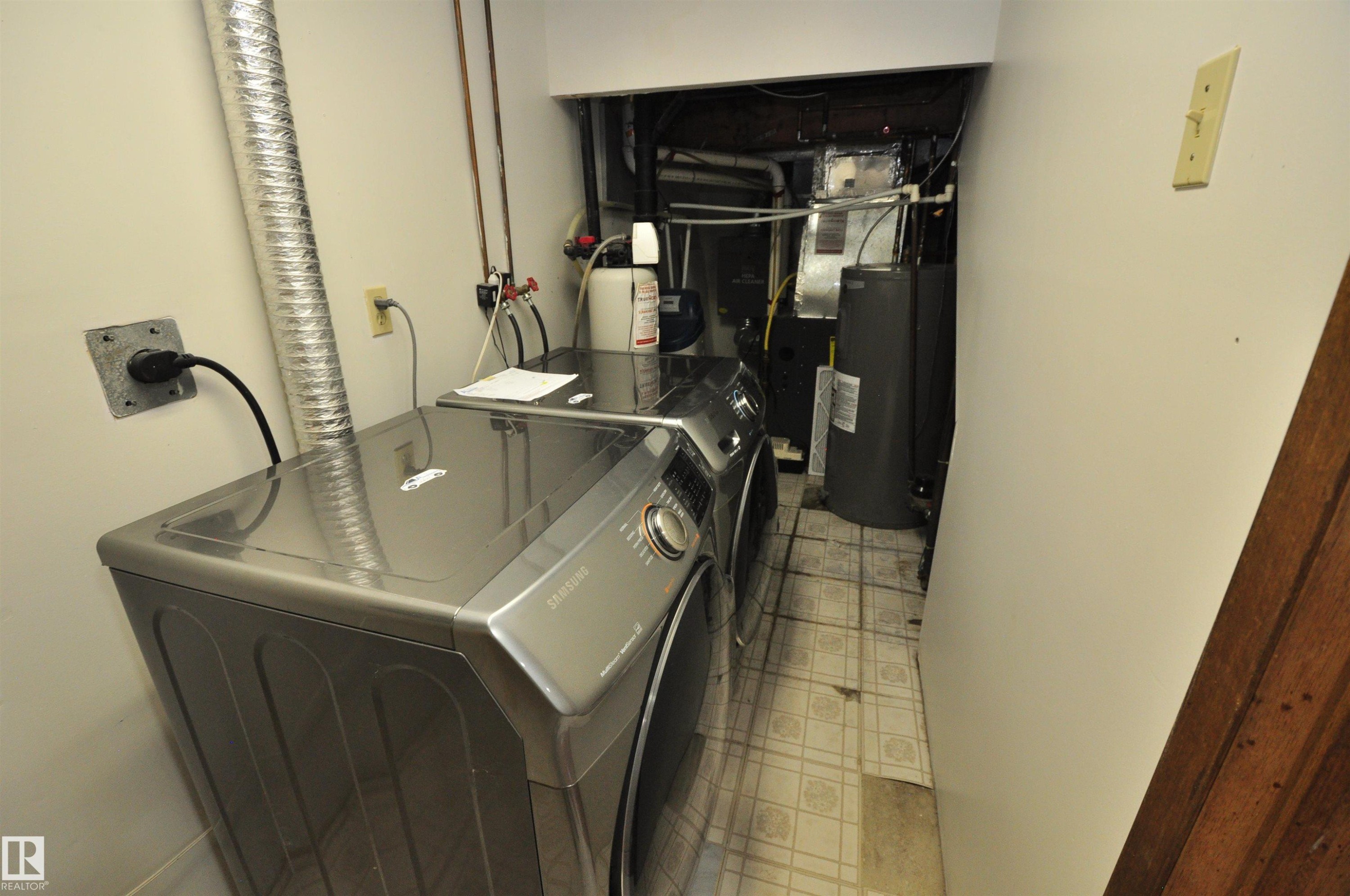 Dedicated laundry area featuring a washer and dryer, utility connections, and vinyl tile flooring - 617 Millbourne Road E, Edmonton, AB
