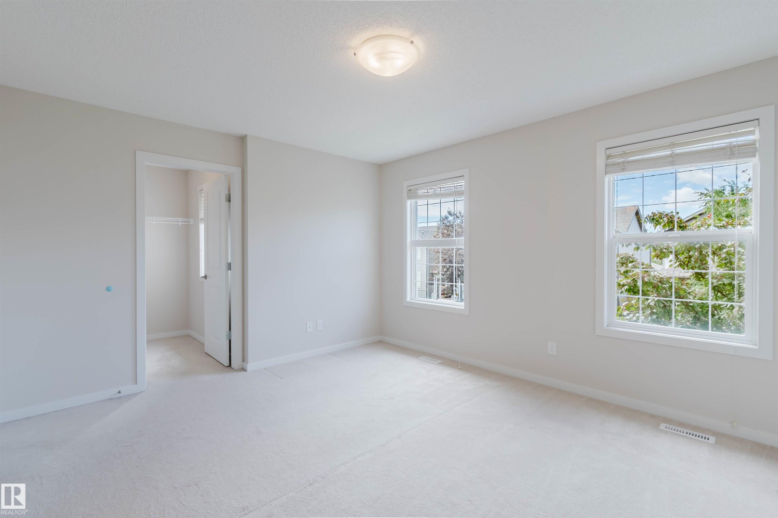 Carpeted room with multiple windows, a ceiling-mounted light fixture, and a closet with bifold doors - 636 Mcdonough Link Link, Edmonton, AB