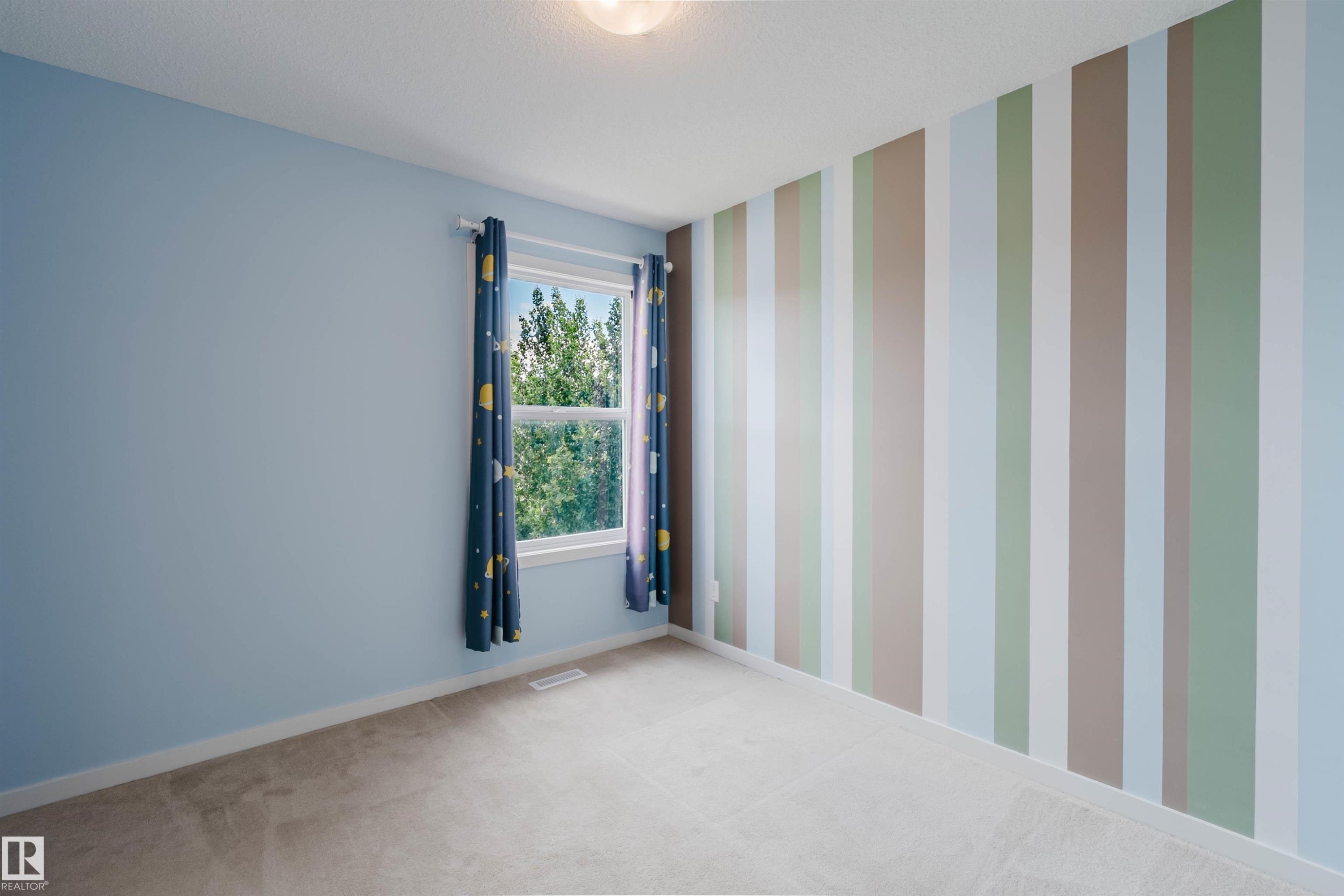 Room featuring a striped accent wall, light blue wall paint, a double-hung window, and neutral carpeting - 636 Mcdonough Link Link, Edmonton, AB