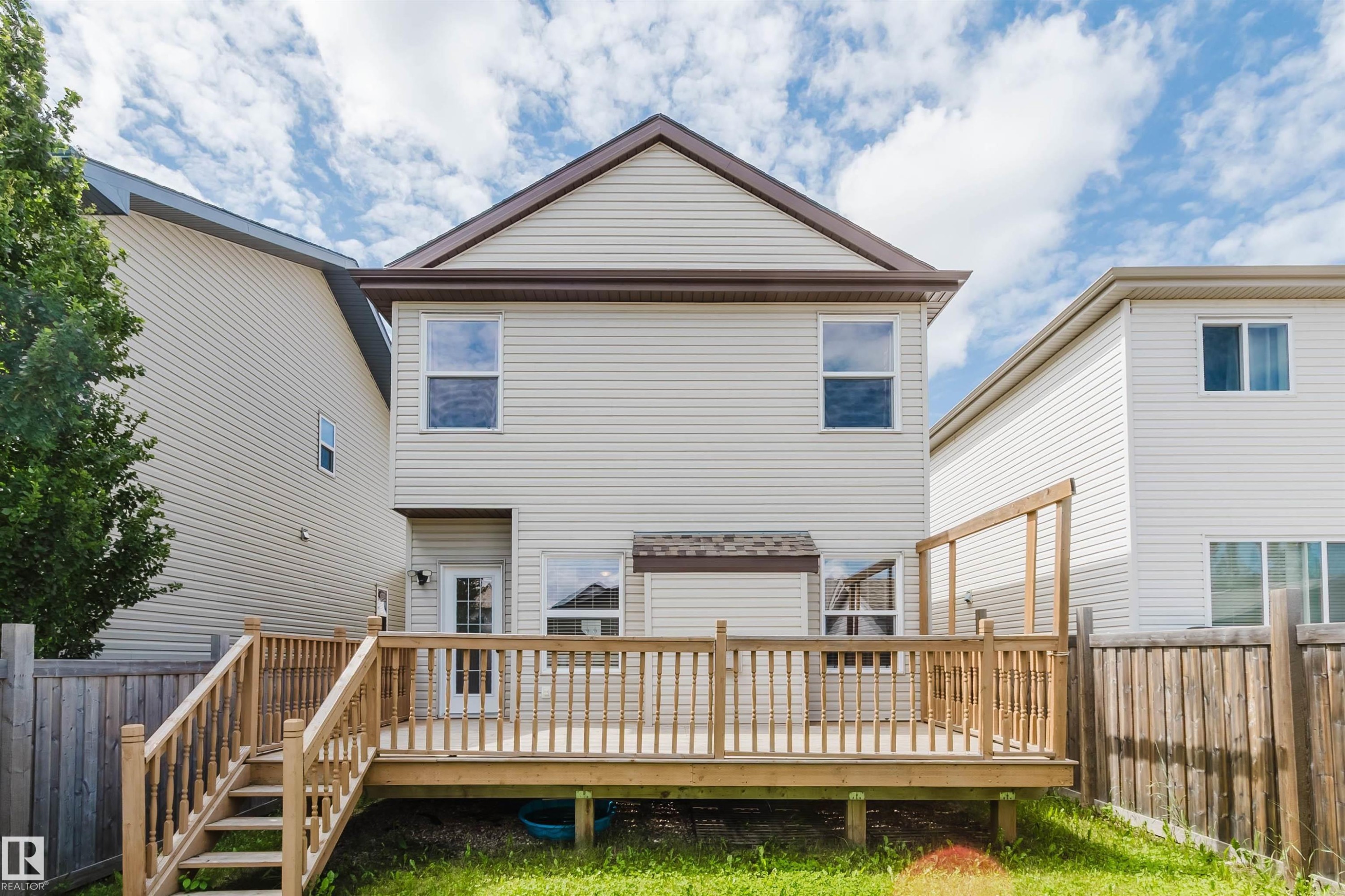 Rear exterior featuring a spacious wooden deck with railings and stairs - 636 Mcdonough Link Link, Edmonton, AB