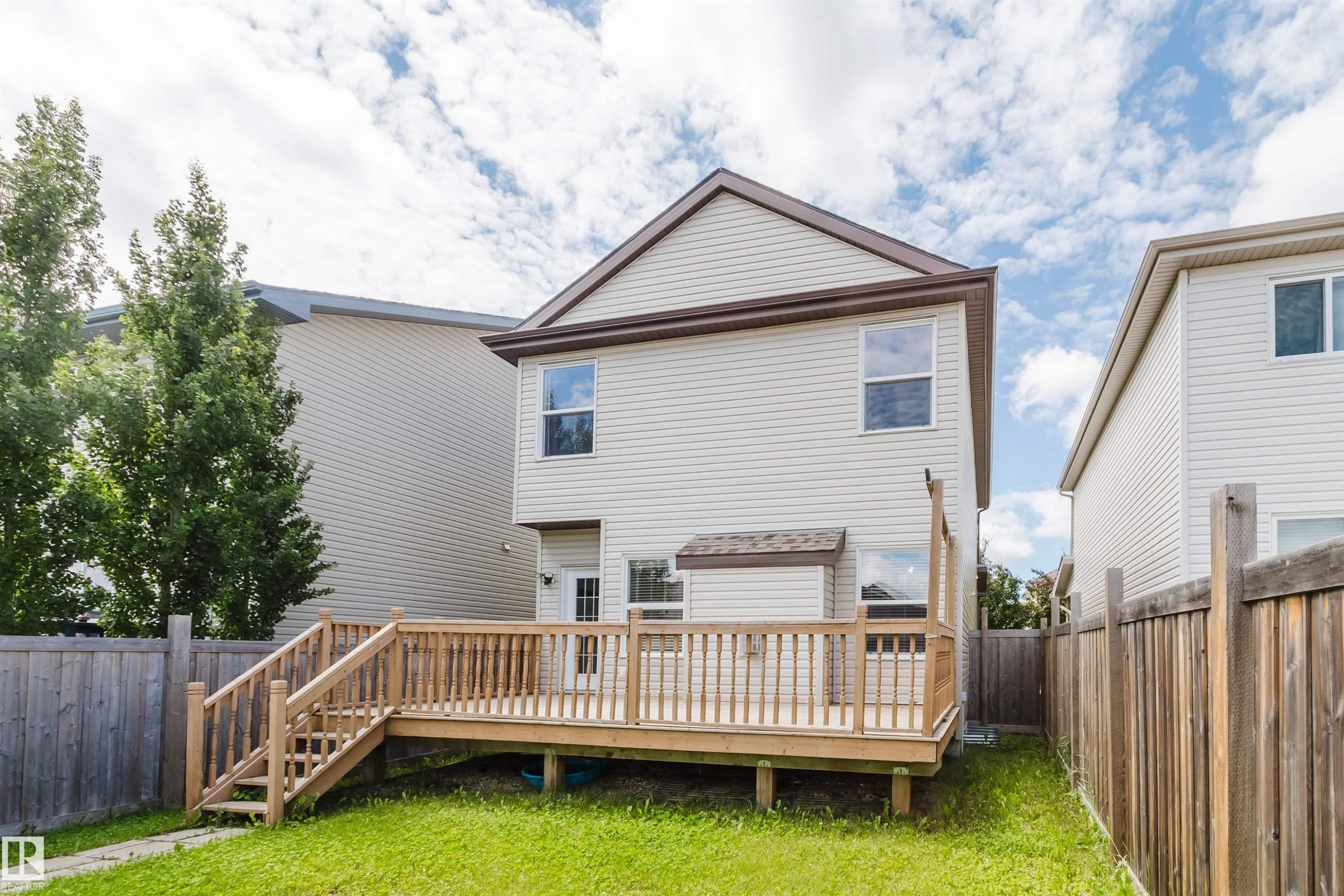 Expansive backyard featuring a large wooden deck with full balustrade, a grass lawn, and wood privacy fencing - 636 Mcdonough Link Link, Edmonton, AB