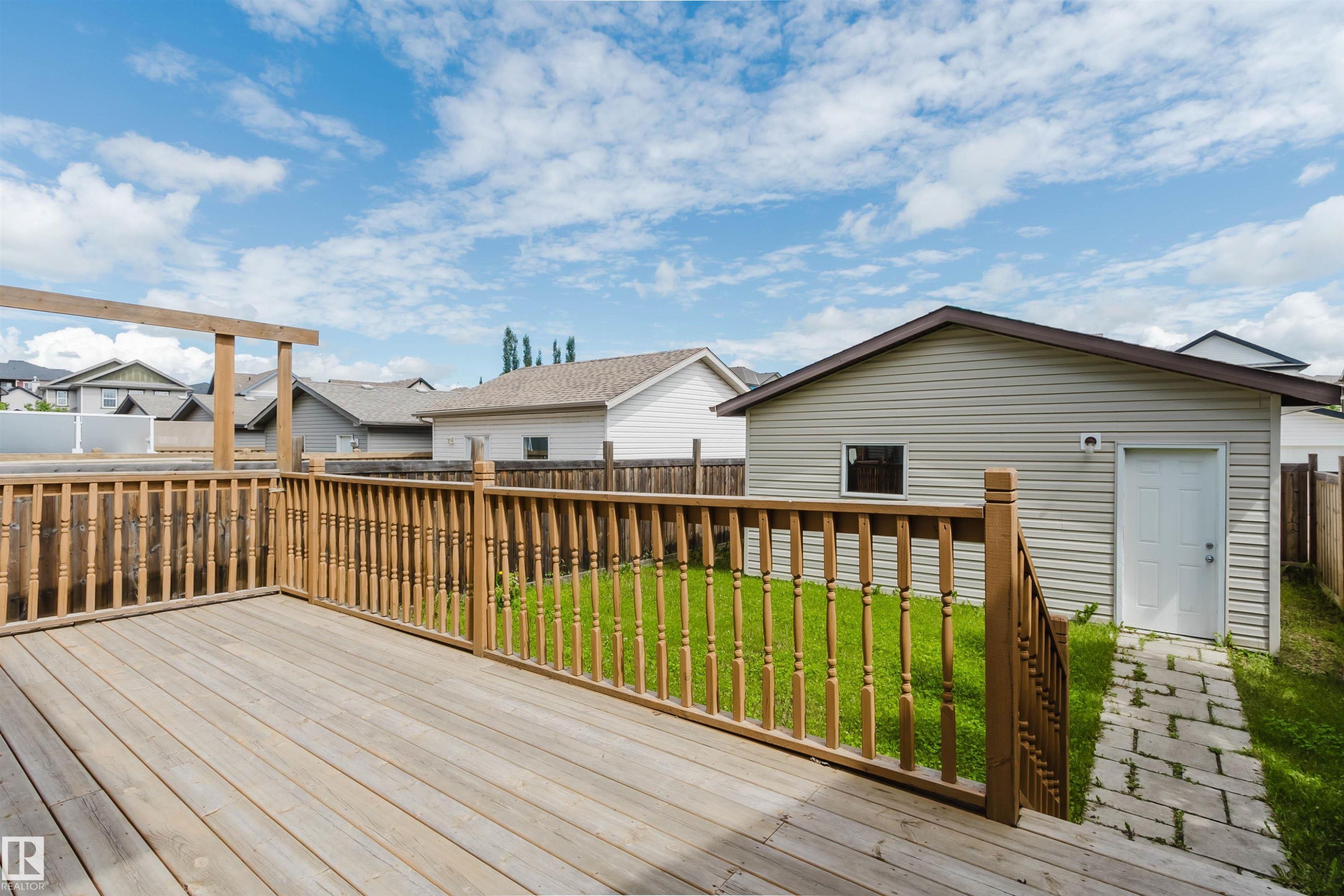 Spacious wooden deck with a slatted railing, overlooking a green lawn - 636 Mcdonough Link Link, Edmonton, AB