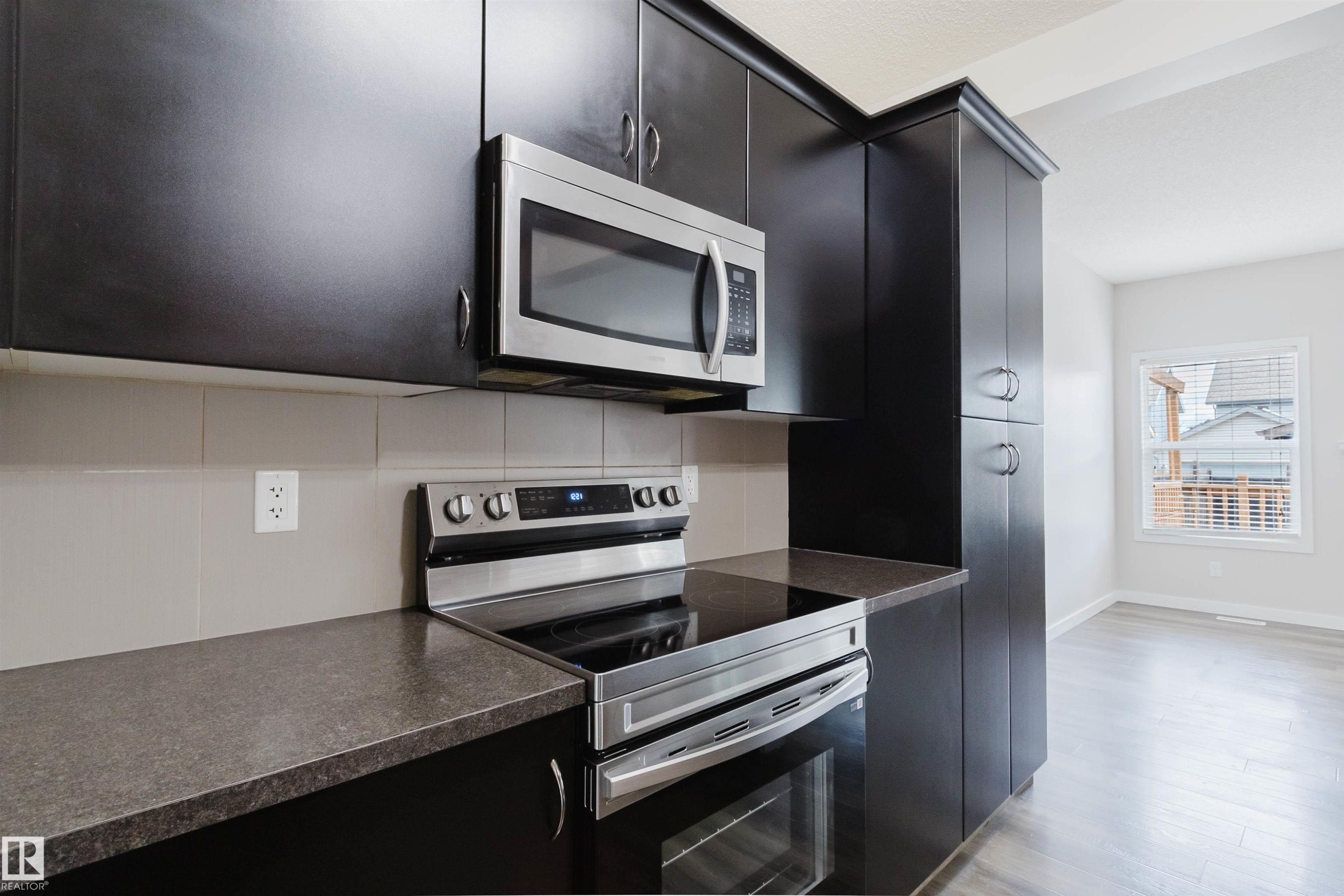 Modern kitchen featuring dark wood-finish cabinetry and stainless steel appliances - 636 Mcdonough Link Link, Edmonton, AB
