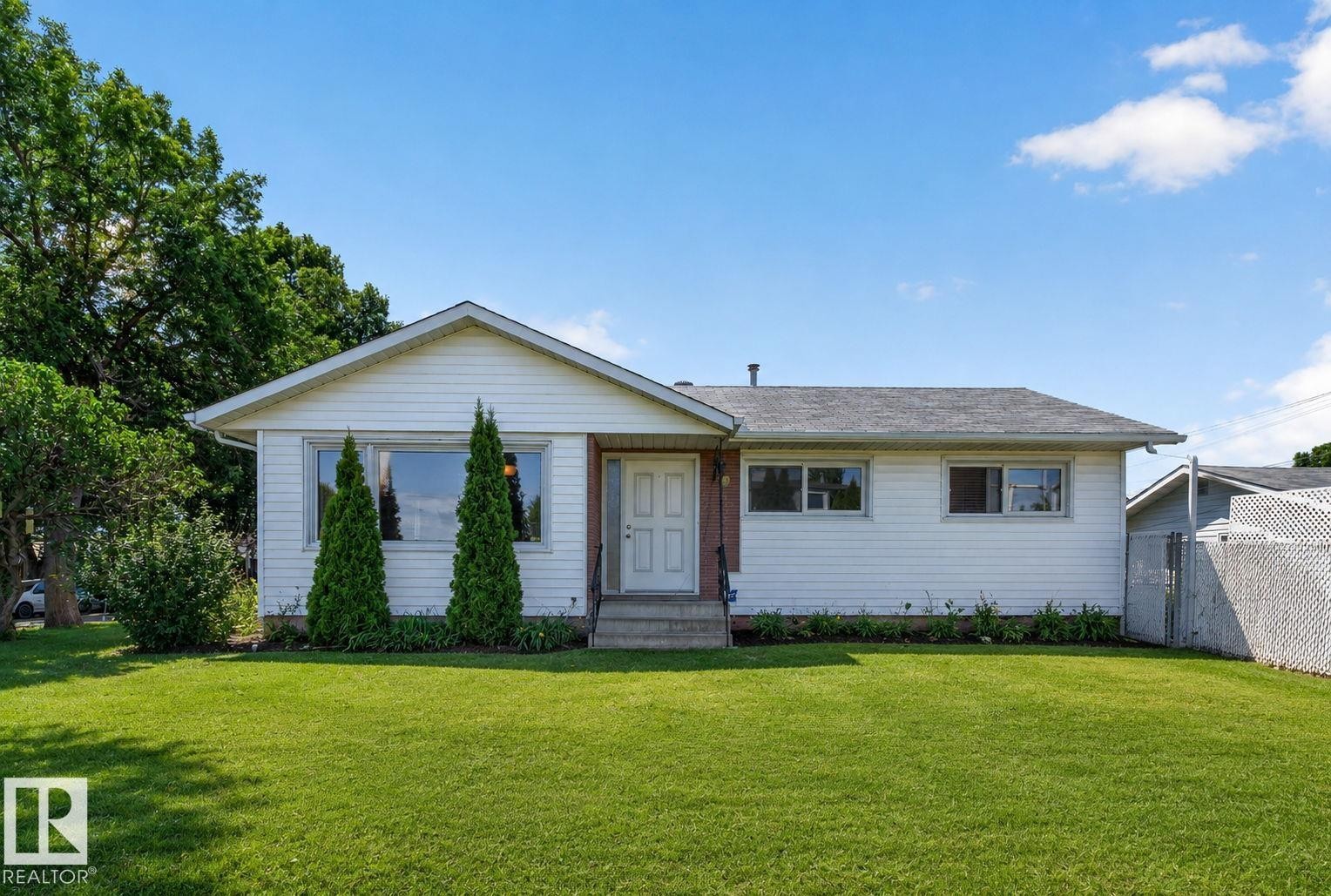 Single-story residence featuring white siding, a dark gray shingle roof, and a prominent front gable - 12238 48 Street, Edmonton, AB