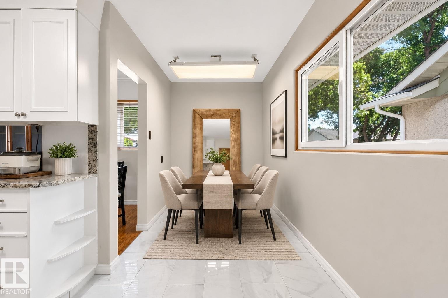 White shaker cabinetry with granite countertops, built-in shelving, and a wood-finish dining table - 12238 48 Street, Edmonton, AB