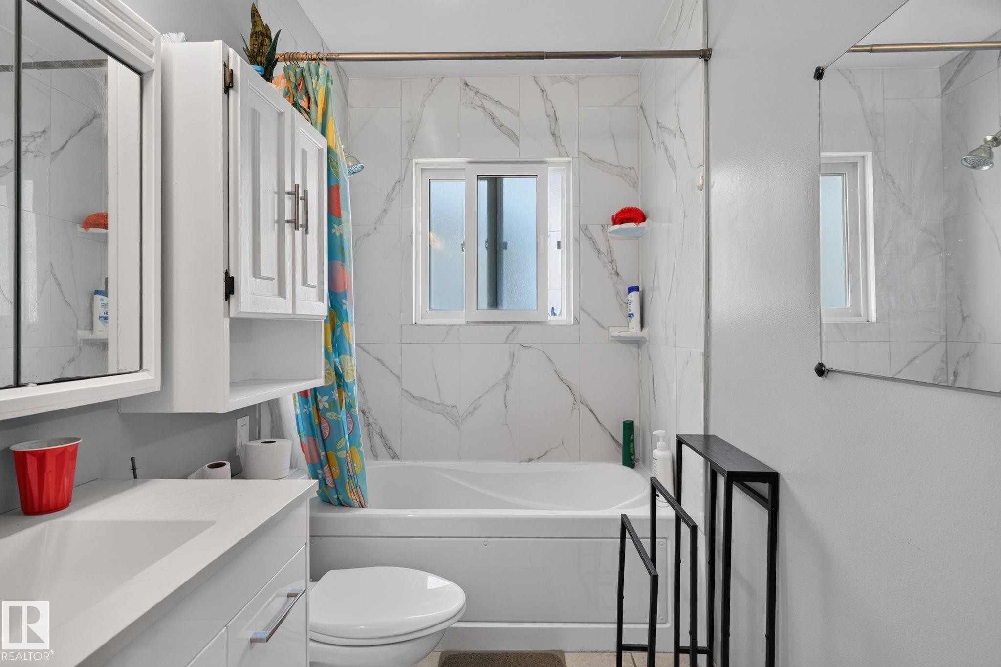 Bathroom featuring a white bathtub, white wall tiles with gray veining, and a window above the tub - 12238 48 Street, Edmonton, AB