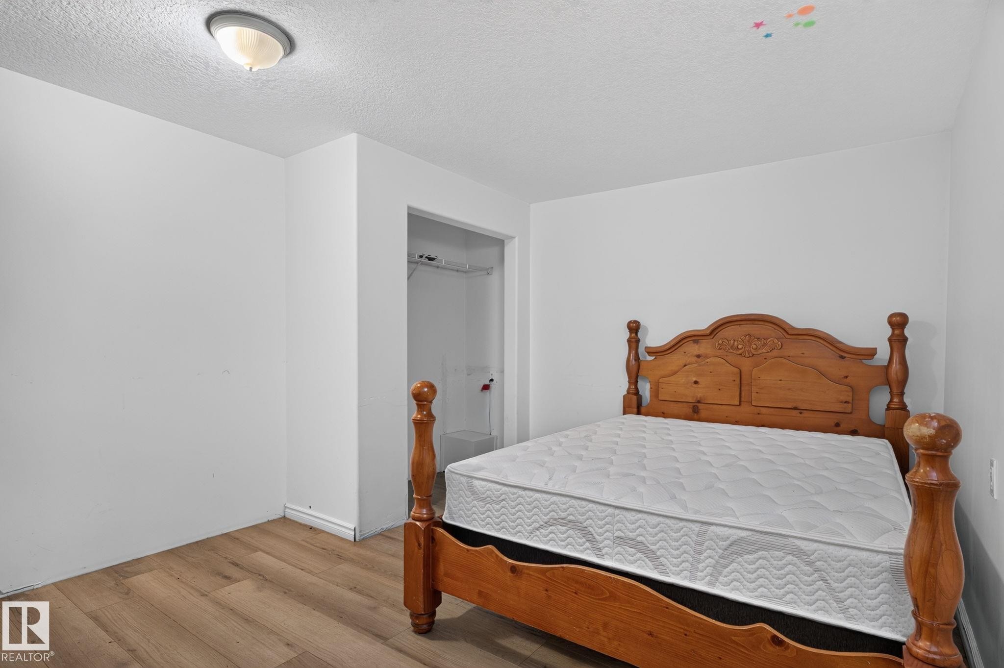 Room featuring wood-finish flooring, white painted walls, and a flush-mount ceiling light fixture - 12238 48 Street, Edmonton, AB