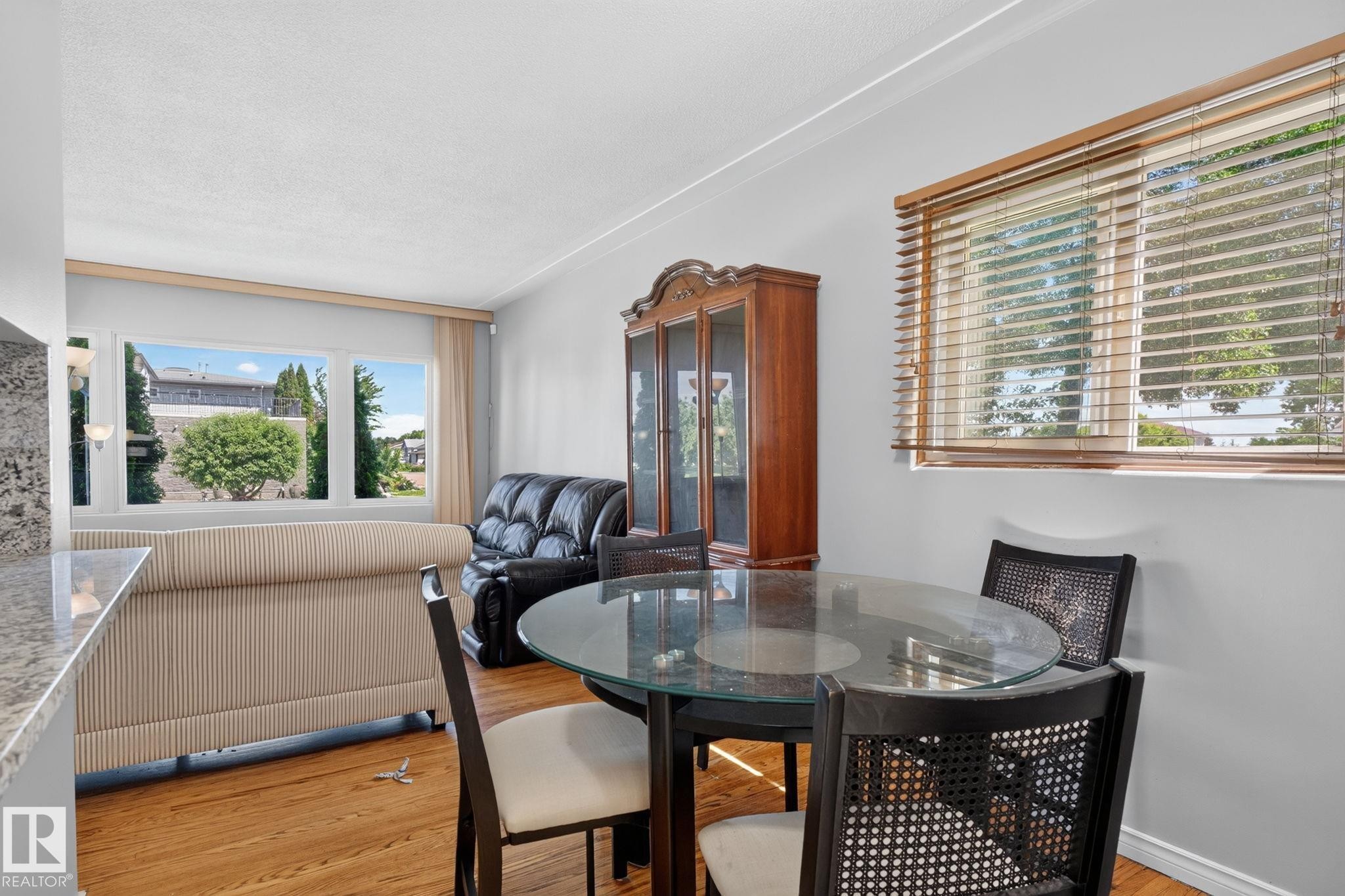 Open-concept living and dining area featuring warm wood-finish flooring - 12238 48 Street, Edmonton, AB