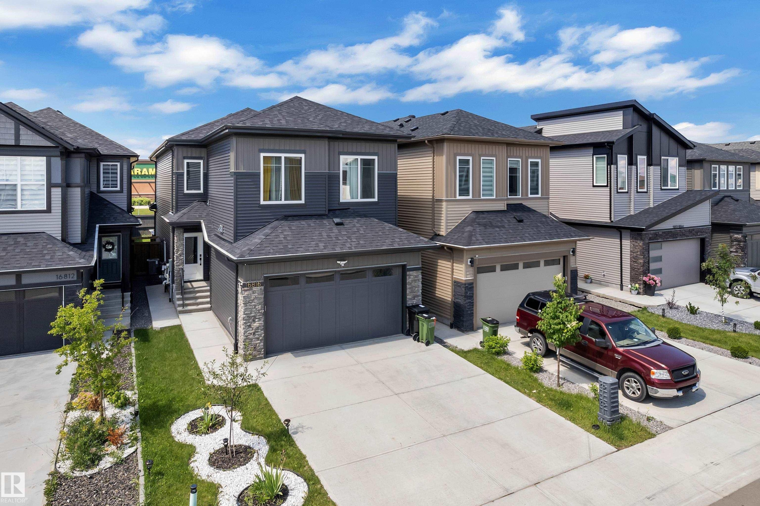 Contemporary two-story residence featuring a dark gray and light gray siding exterior with stone accents - 16816 49 Street, Edmonton, AB