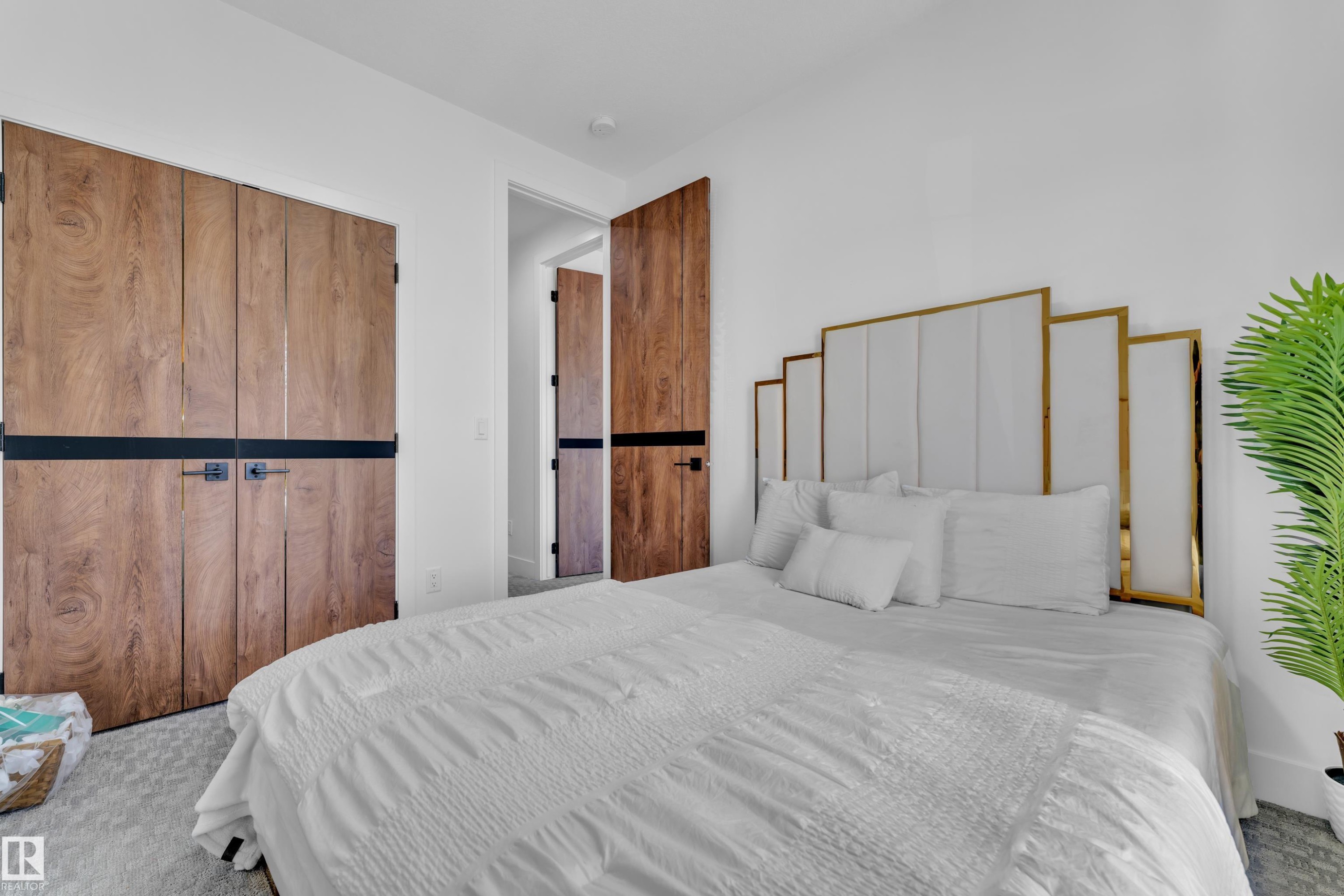 Bedroom featuring light wood-finish doors with horizontal black banding, white walls, and light-toned carpet flooring - 16816 49 Street, Edmonton, AB